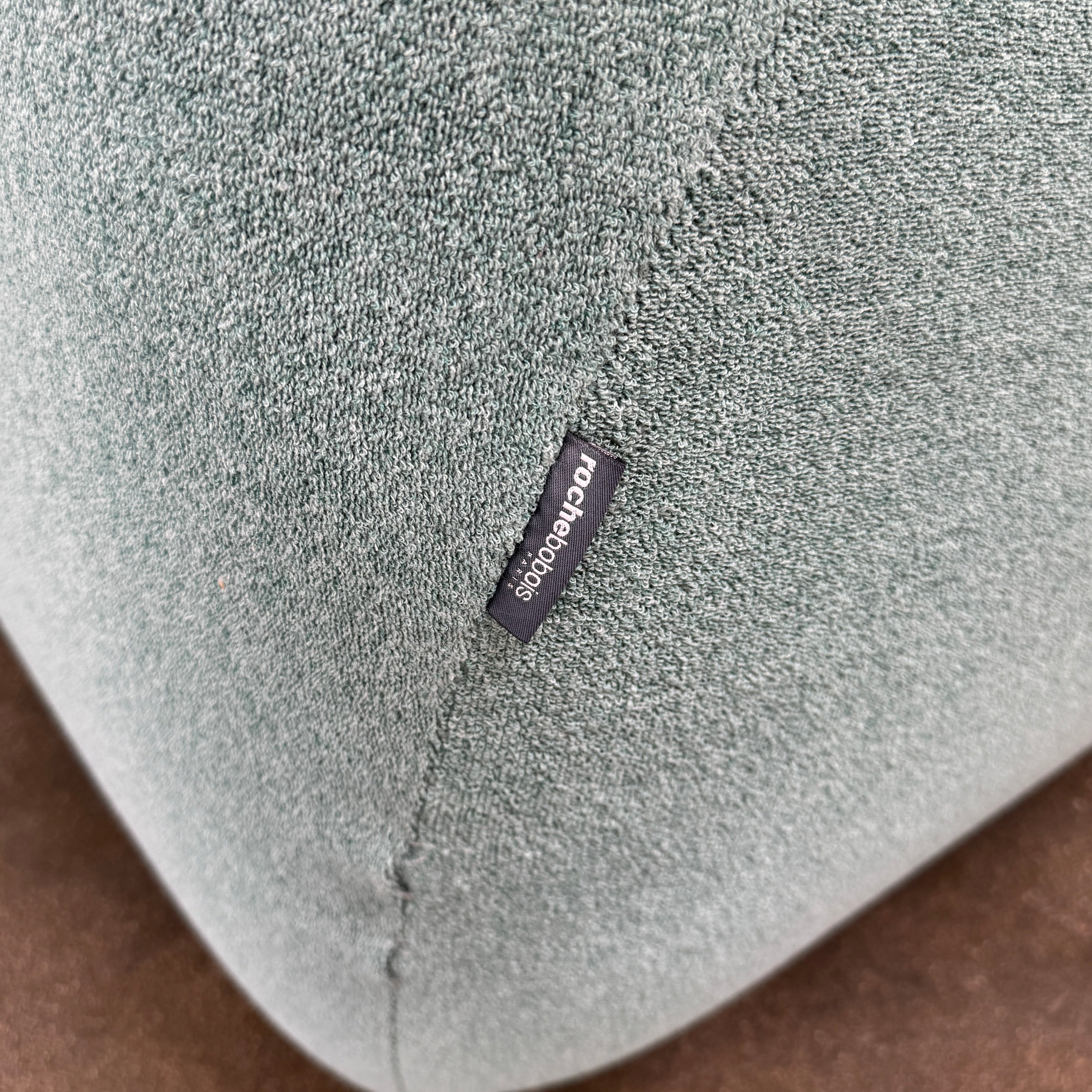 The Roche Bobois Informel Outdoor Large 3-seat Sofa Low Back features a light teal modern design with rounded edges, button-tufted details, and advanced outdoor fabric technology, inspired by Roche Bobois’s signature style.
