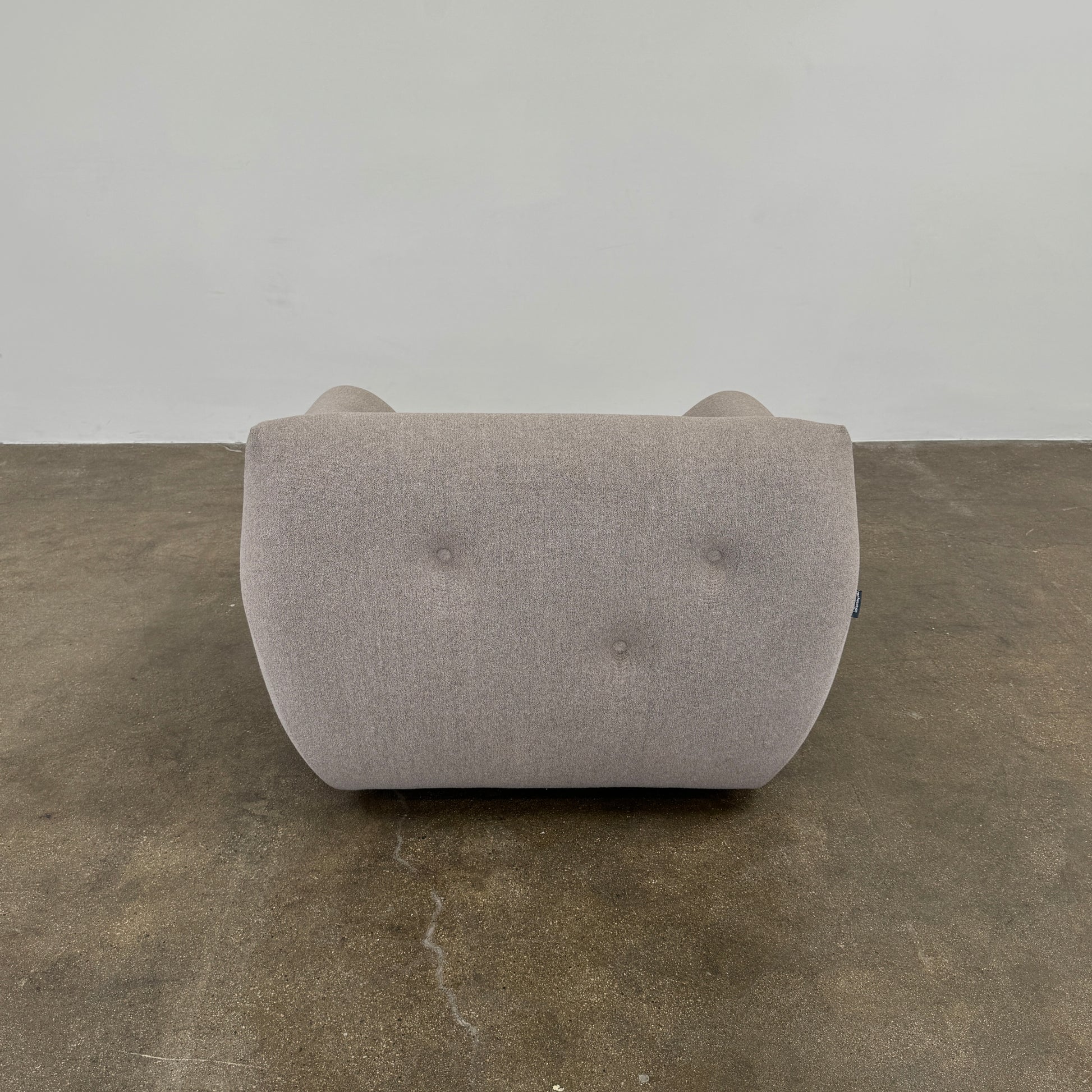 The Roche Bobois Informel Outdoor Low Back Armchair by Roche Bobois features modern, light gray upholstery with rounded arms and tufted button details for plush comfort, shown from the front on a white background.
