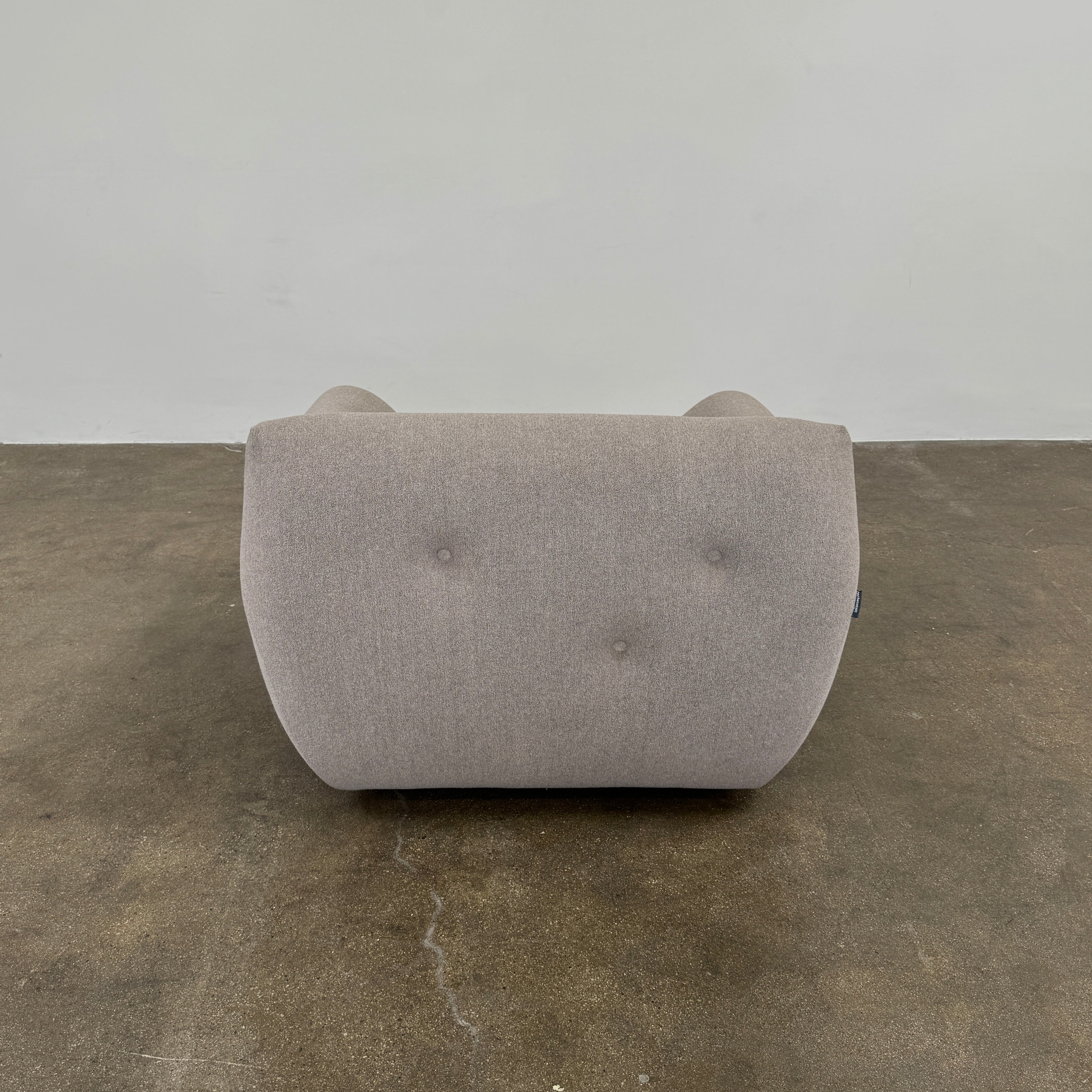 The Roche Bobois Informel Outdoor Low Back Armchair by Roche Bobois features modern, light gray upholstery with rounded arms and tufted button details for plush comfort, shown from the front on a white background.