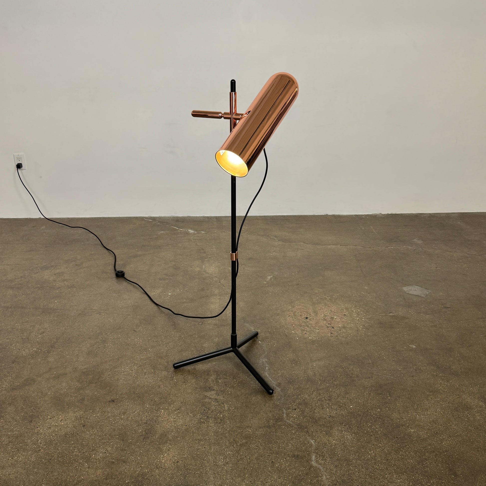 The Roche Bobois Wander Floor lamp features a cylindrical copper shade, black stand, and tripod base with attached power cord—an elegant, modern addition inspired by Roche Bobois design.