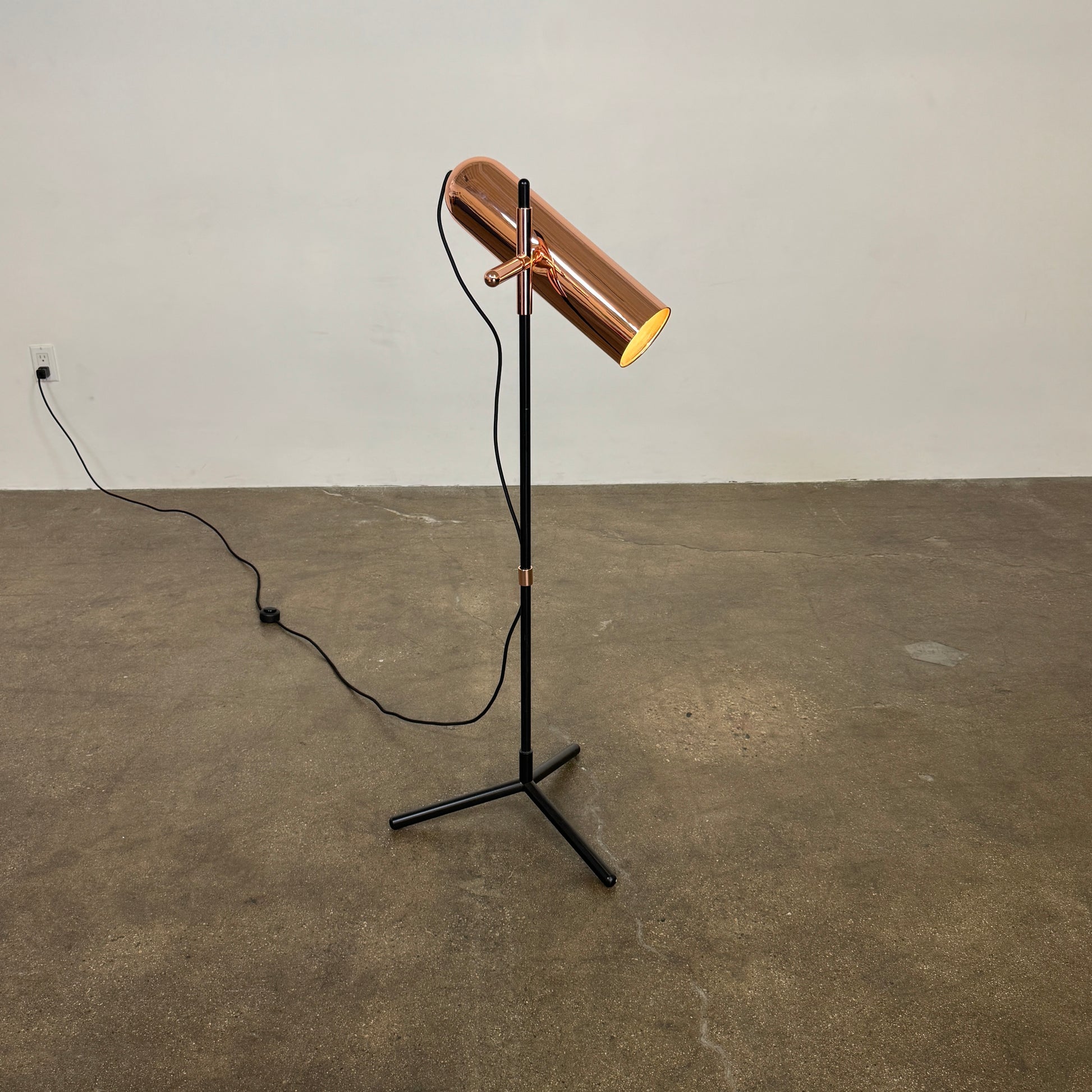 The Roche Bobois Wander Floor lamp features a cylindrical copper shade, black stand, and tripod base with attached power cord—an elegant, modern addition inspired by Roche Bobois design.