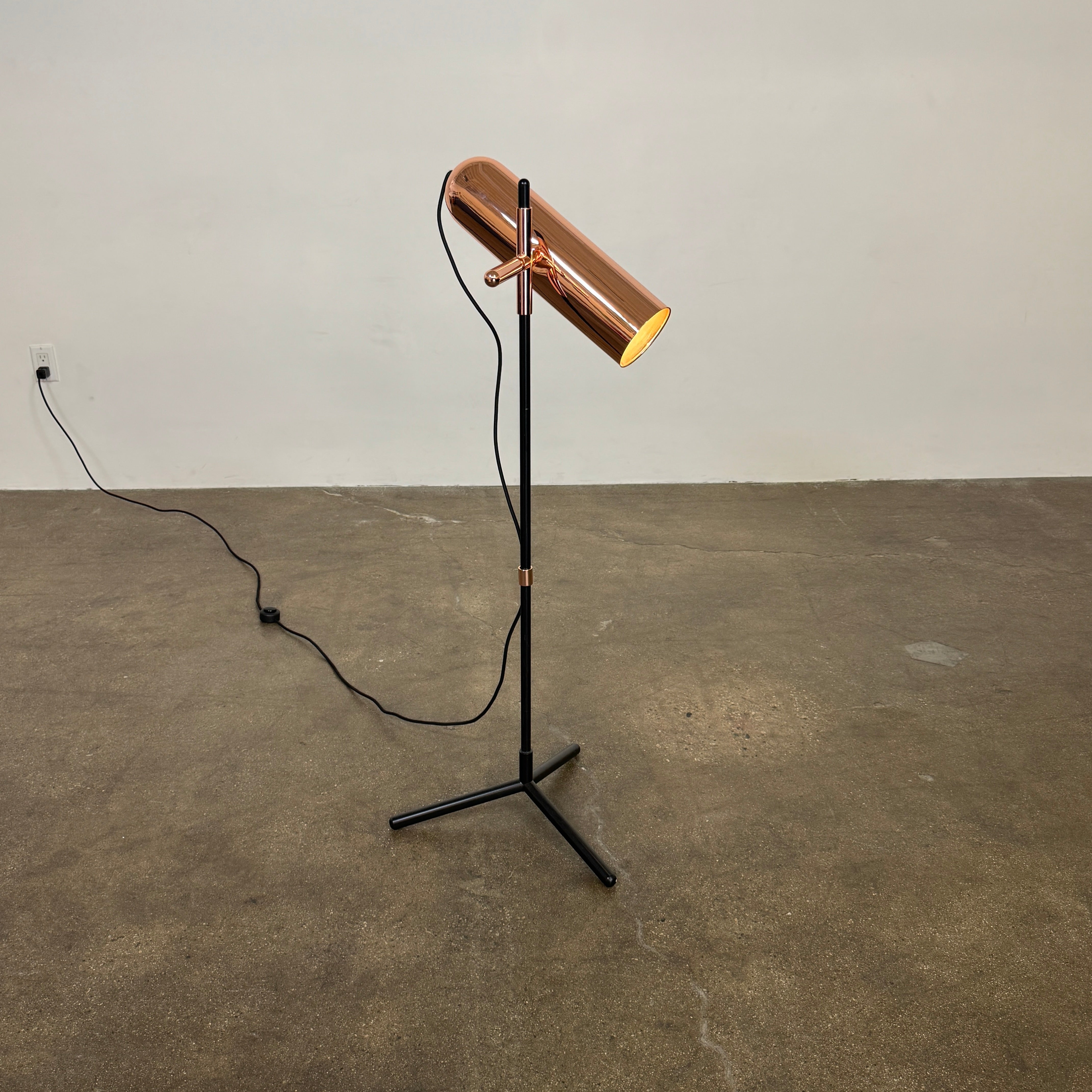 The Roche Bobois Wander Floor lamp features a cylindrical copper shade, black stand, and tripod base with attached power cord—an elegant, modern addition inspired by Roche Bobois design.