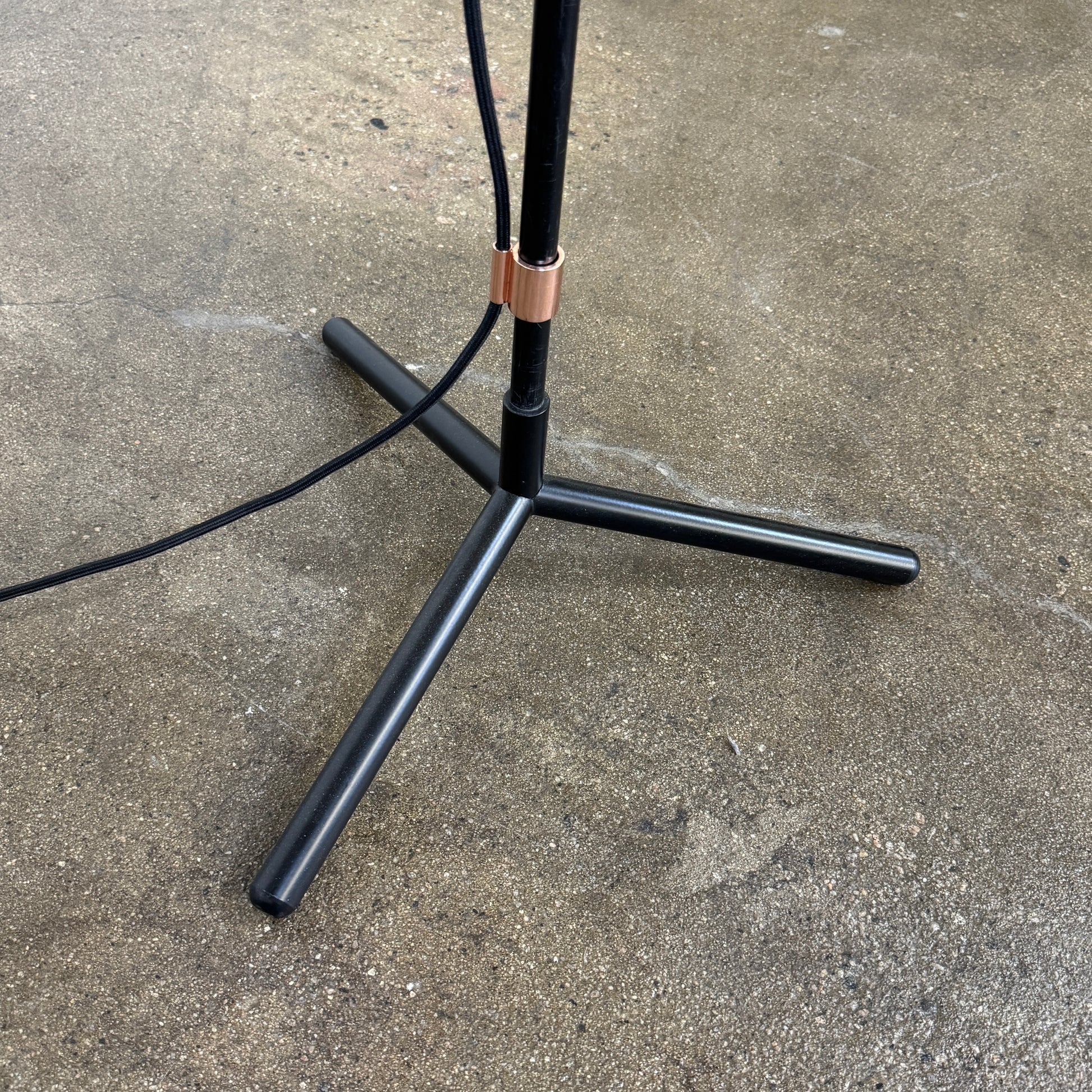 The Roche Bobois Wander Floor lamp features a cylindrical copper shade, black stand, and tripod base with attached power cord—an elegant, modern addition inspired by Roche Bobois design.