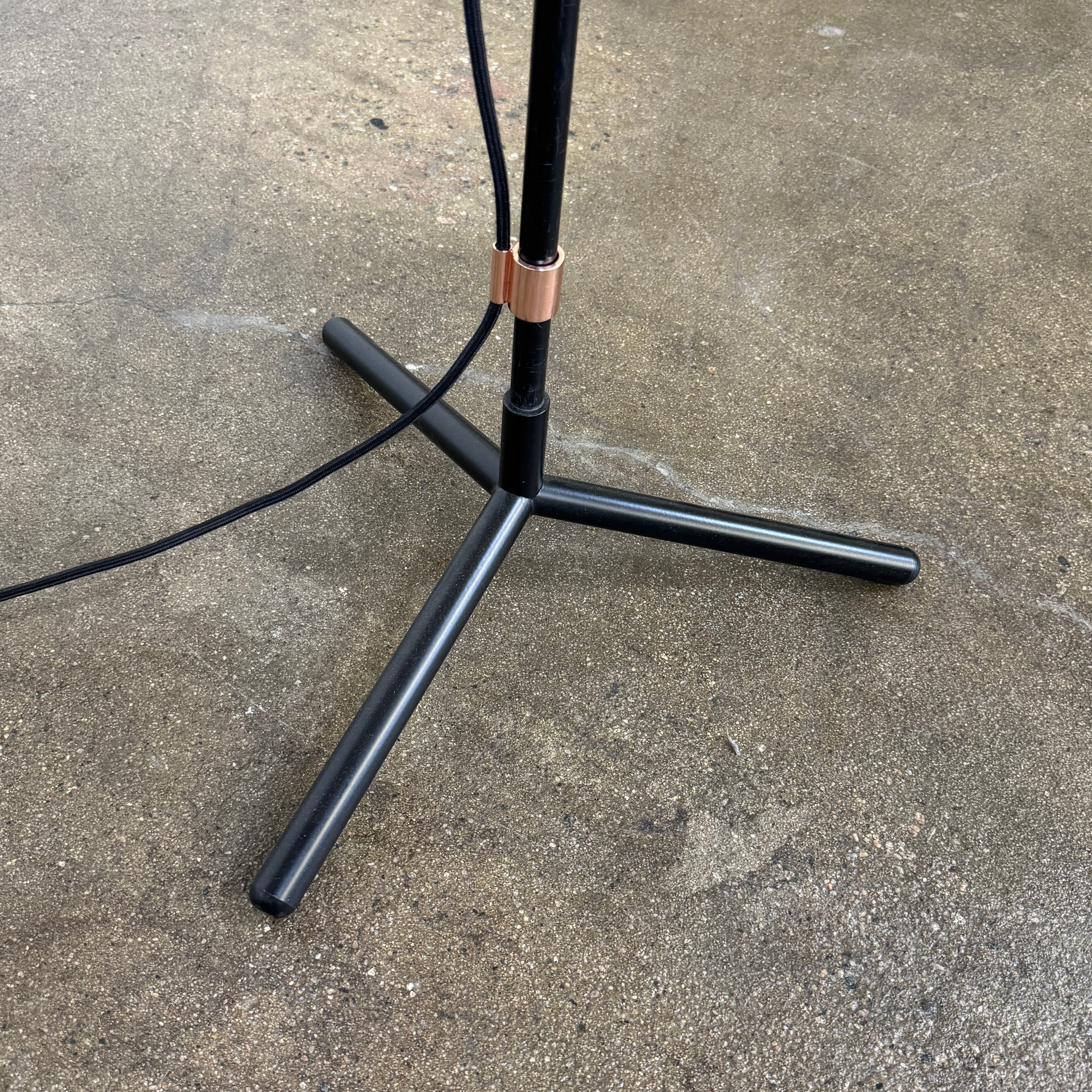 The Roche Bobois Wander Floor lamp features a cylindrical copper shade, black stand, and tripod base with attached power cord—an elegant, modern addition inspired by Roche Bobois design.