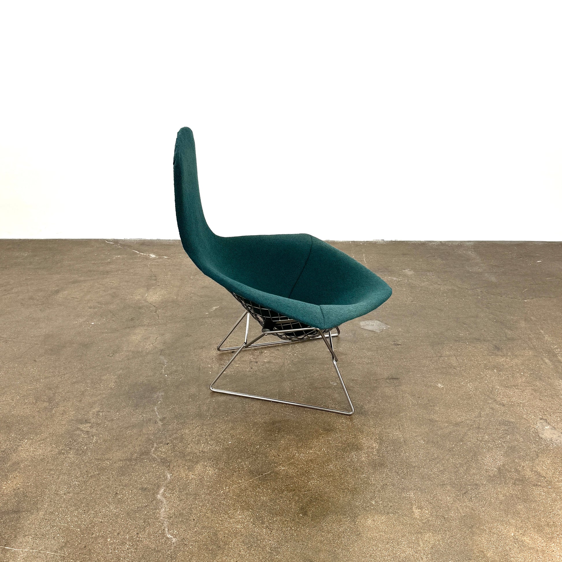 The Vintage Bertoia Bird Chair by Vintage features a modern green upholstered design with a curved backrest and metal wire base, inspired by mid-century style, photographed against a plain white background.