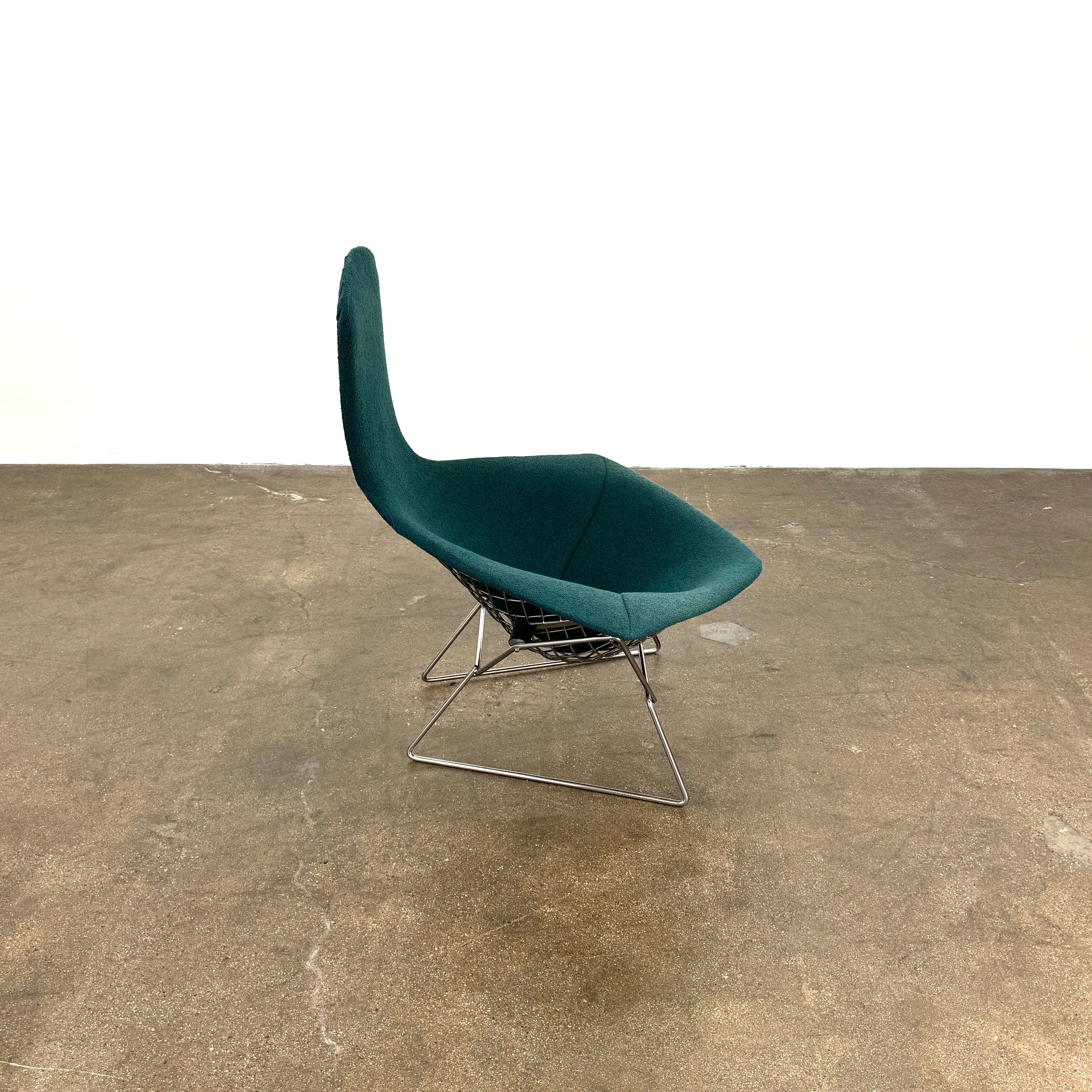 The Vintage Bertoia Bird Chair by Vintage features a modern green upholstered design with a curved backrest and metal wire base, inspired by mid-century style, photographed against a plain white background.