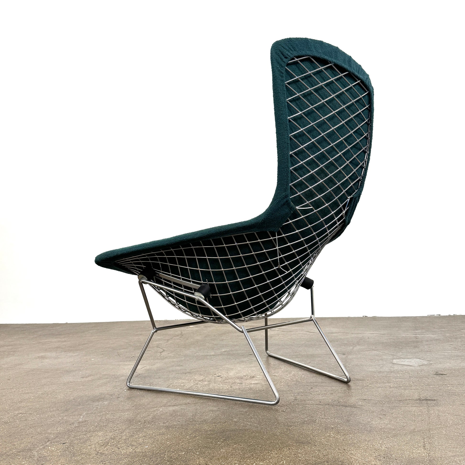 The Vintage Bertoia Bird Chair by Vintage features a modern green upholstered design with a curved backrest and metal wire base, inspired by mid-century style, photographed against a plain white background.