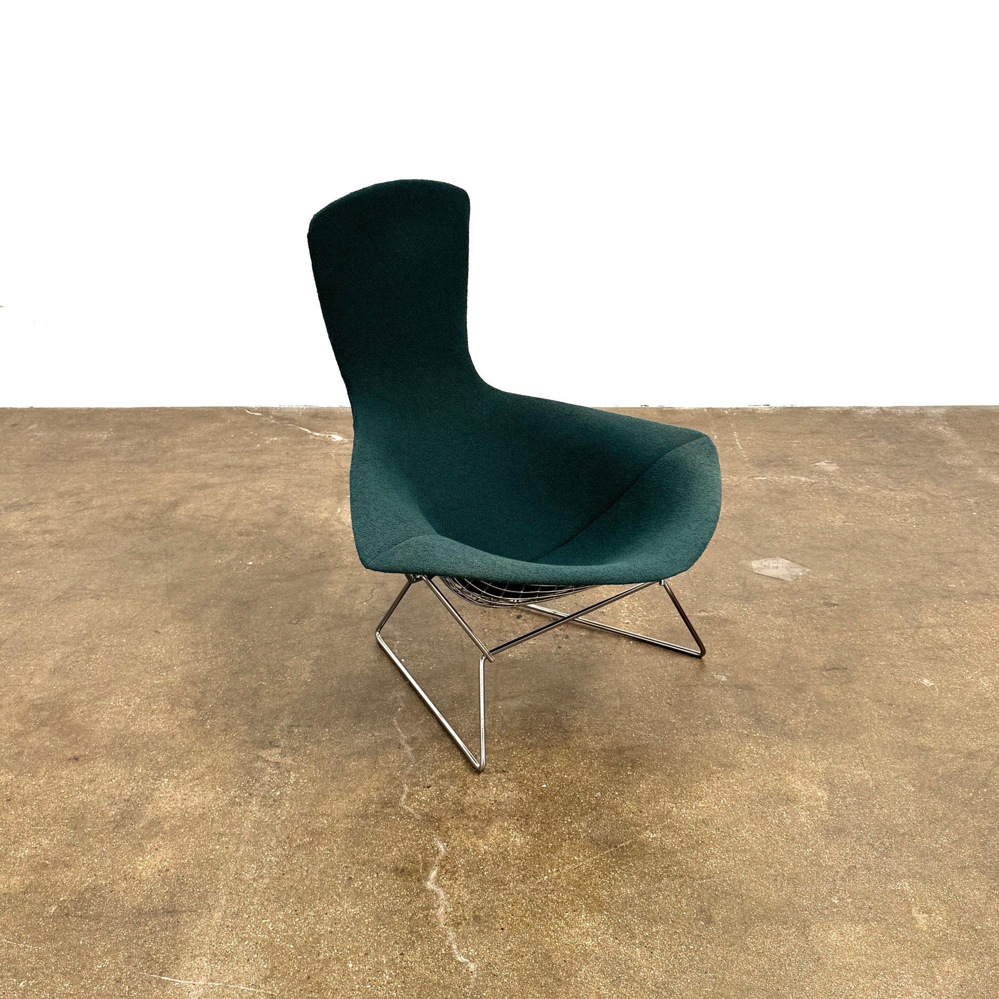 The Vintage Bertoia Bird Chair by Vintage features a modern green upholstered design with a curved backrest and metal wire base, inspired by mid-century style, photographed against a plain white background.