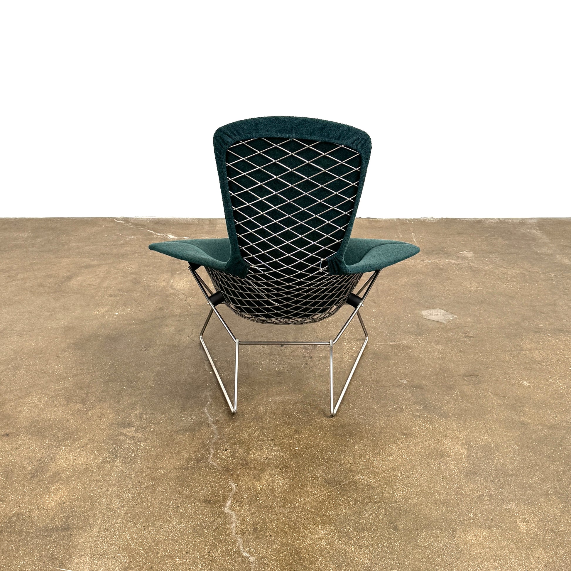 The Vintage Bertoia Bird Chair by Vintage features a modern green upholstered design with a curved backrest and metal wire base, inspired by mid-century style, photographed against a plain white background.