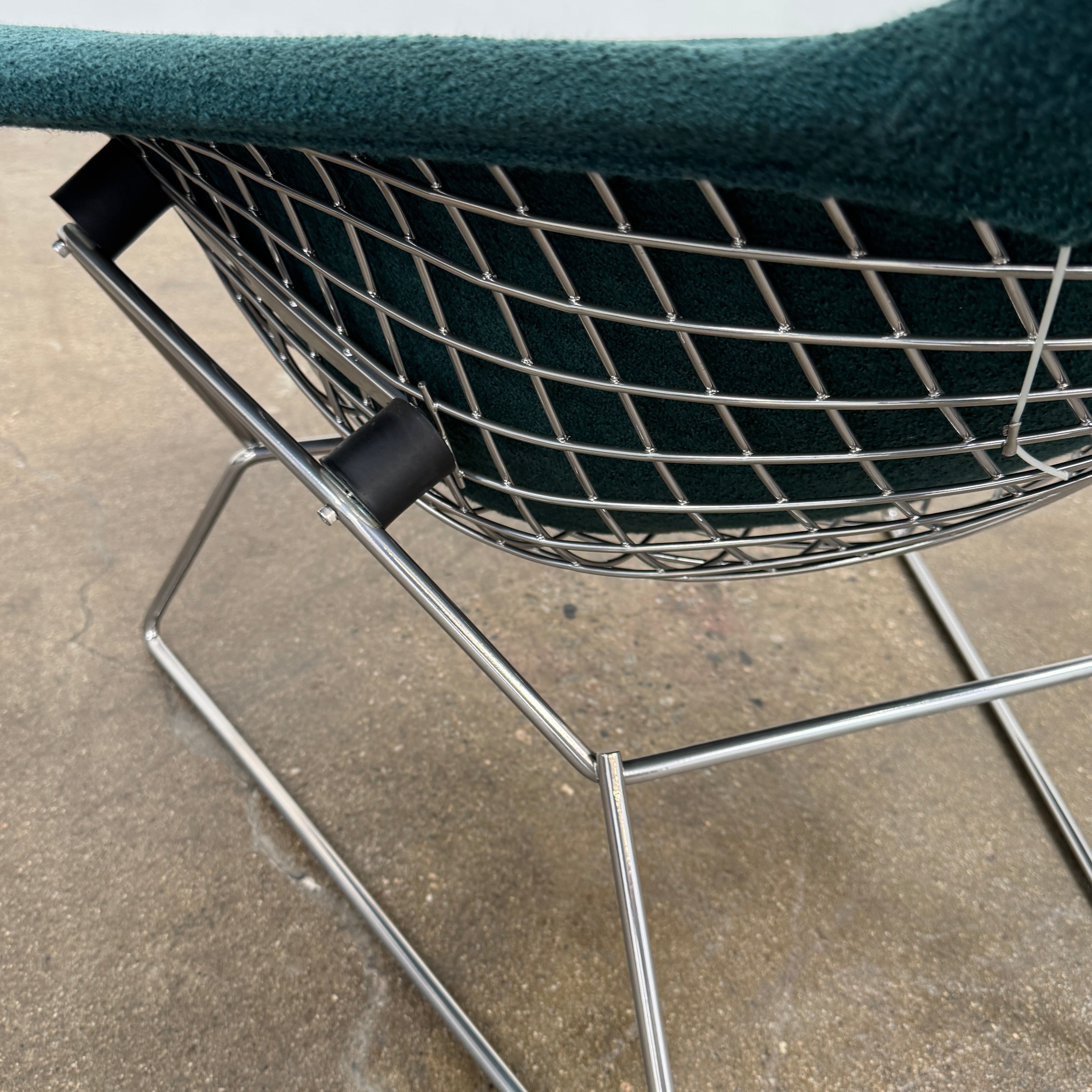 The Vintage Bertoia Bird Chair by Vintage features a modern green upholstered design with a curved backrest and metal wire base, inspired by mid-century style, photographed against a plain white background.