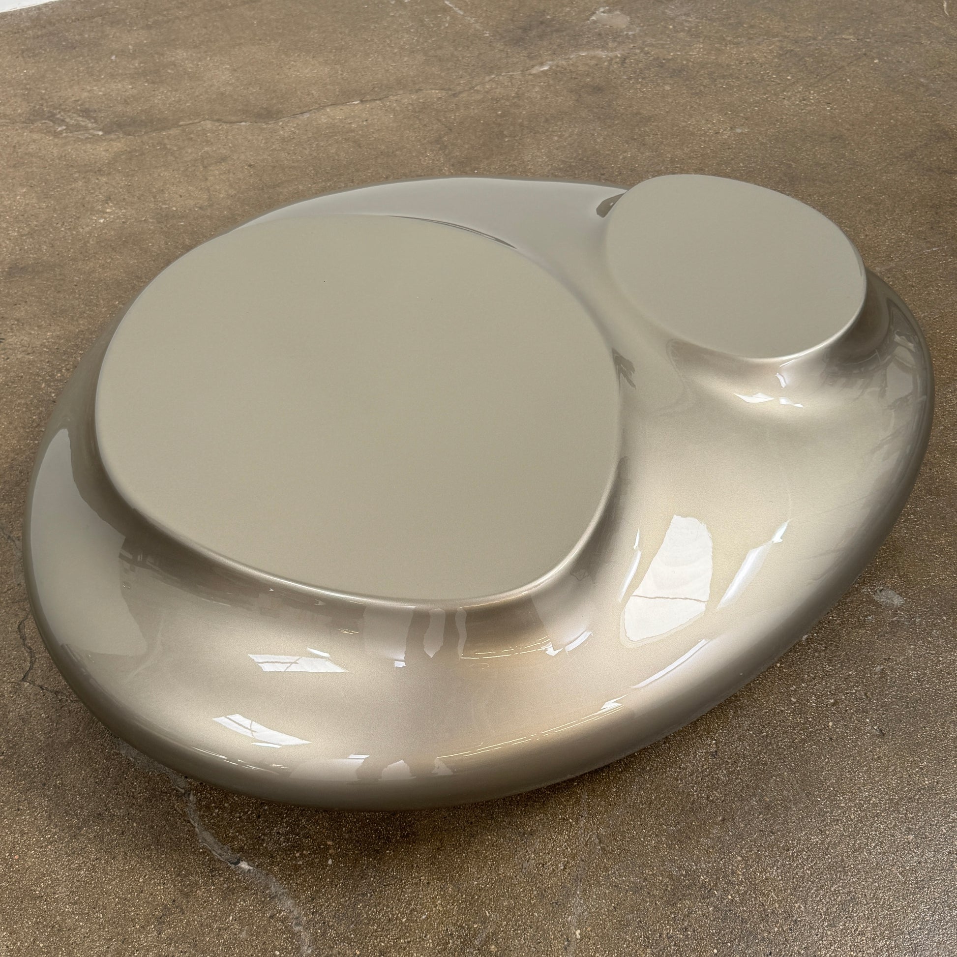 A metallic, smooth, irregularly shaped object with three raised sections on a white background—evoking the sleek Roche Bobois Cute Cut | XXM Cocktail Table, ideal for modern interiors.