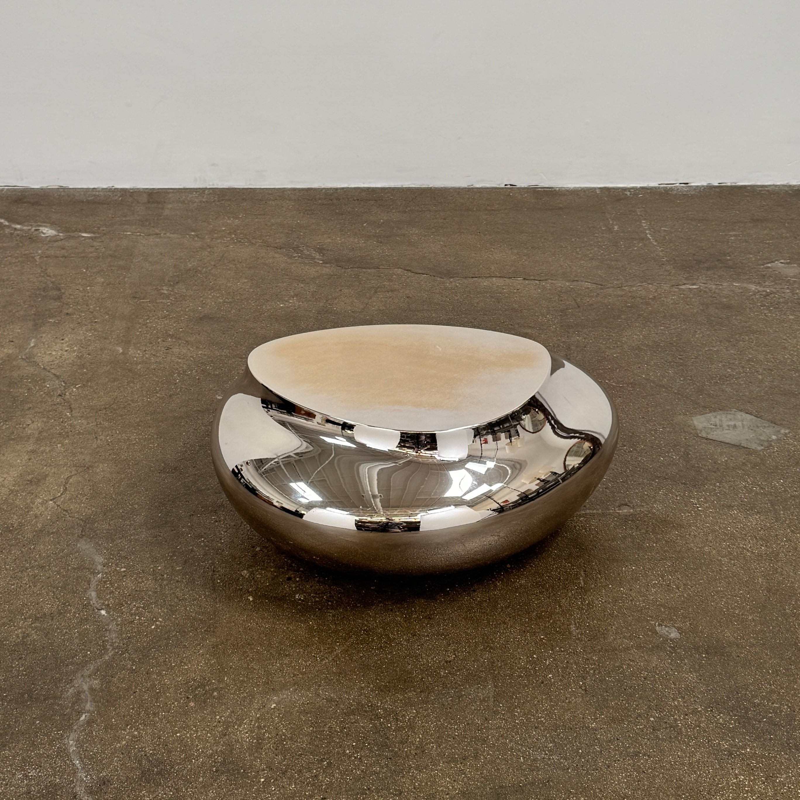 The Roche Bobois cute cut | XXS Cocktail table, with its round, reflective silver surface and smooth, unique shape, stands elegantly against a plain white background—an ideal accent for modern interiors.