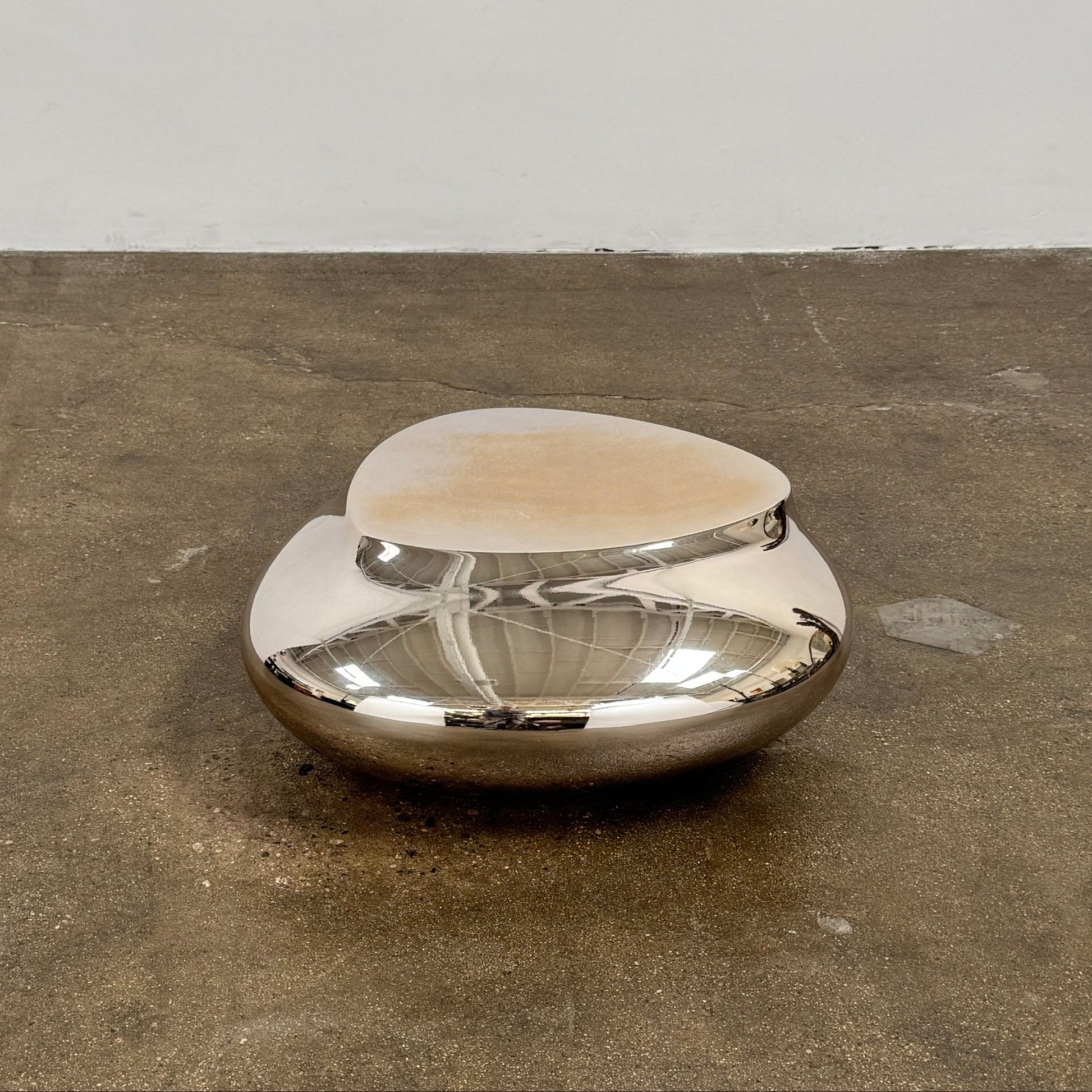 The Roche Bobois cute cut | XXS Cocktail table, with its round, reflective silver surface and smooth, unique shape, stands elegantly against a plain white background—an ideal accent for modern interiors.