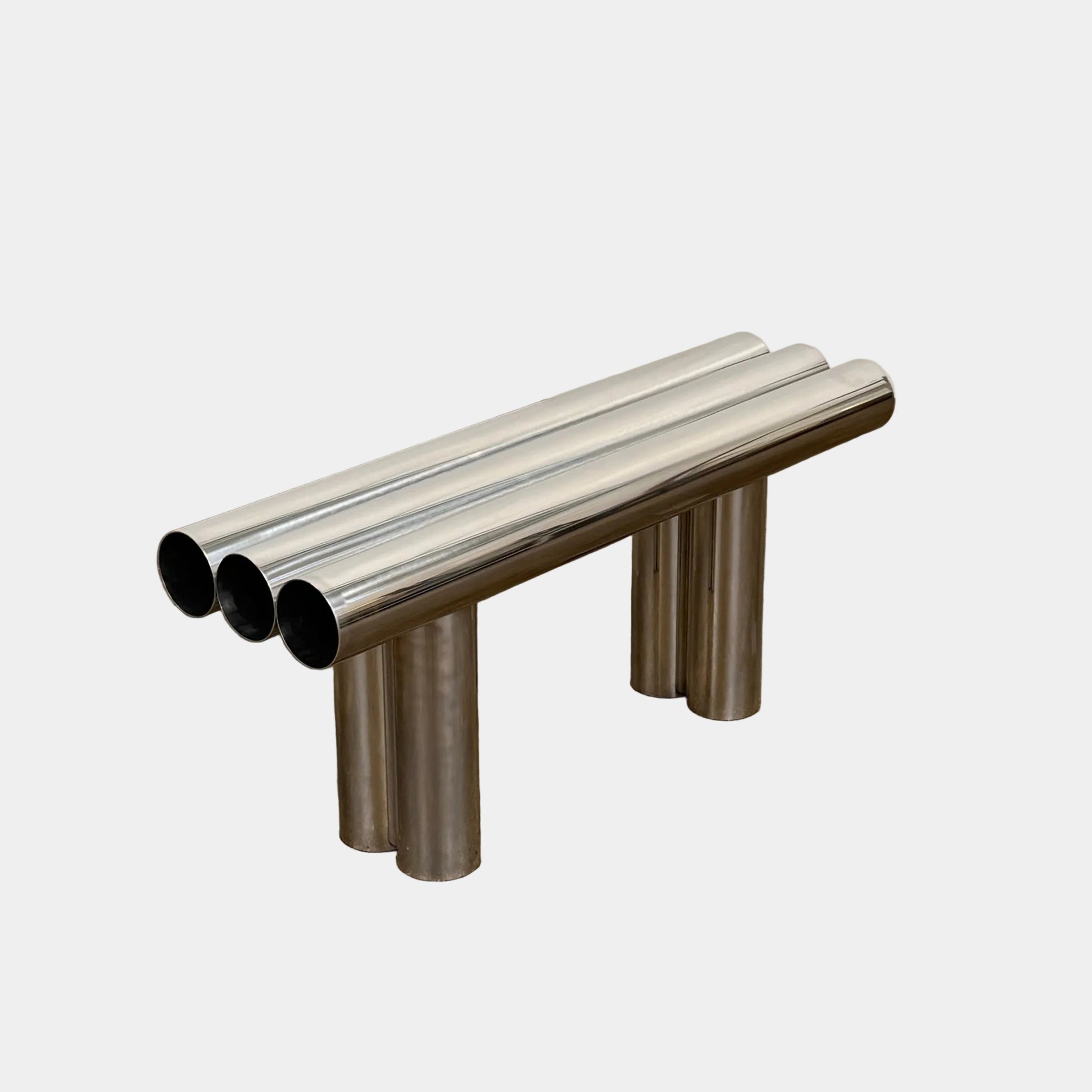 The Future Perfect's Septem Bench by Axel Chay features three cylindrical polished metal seats and matching legs in a Mediterranean-inspired design, shown against a plain white background.
