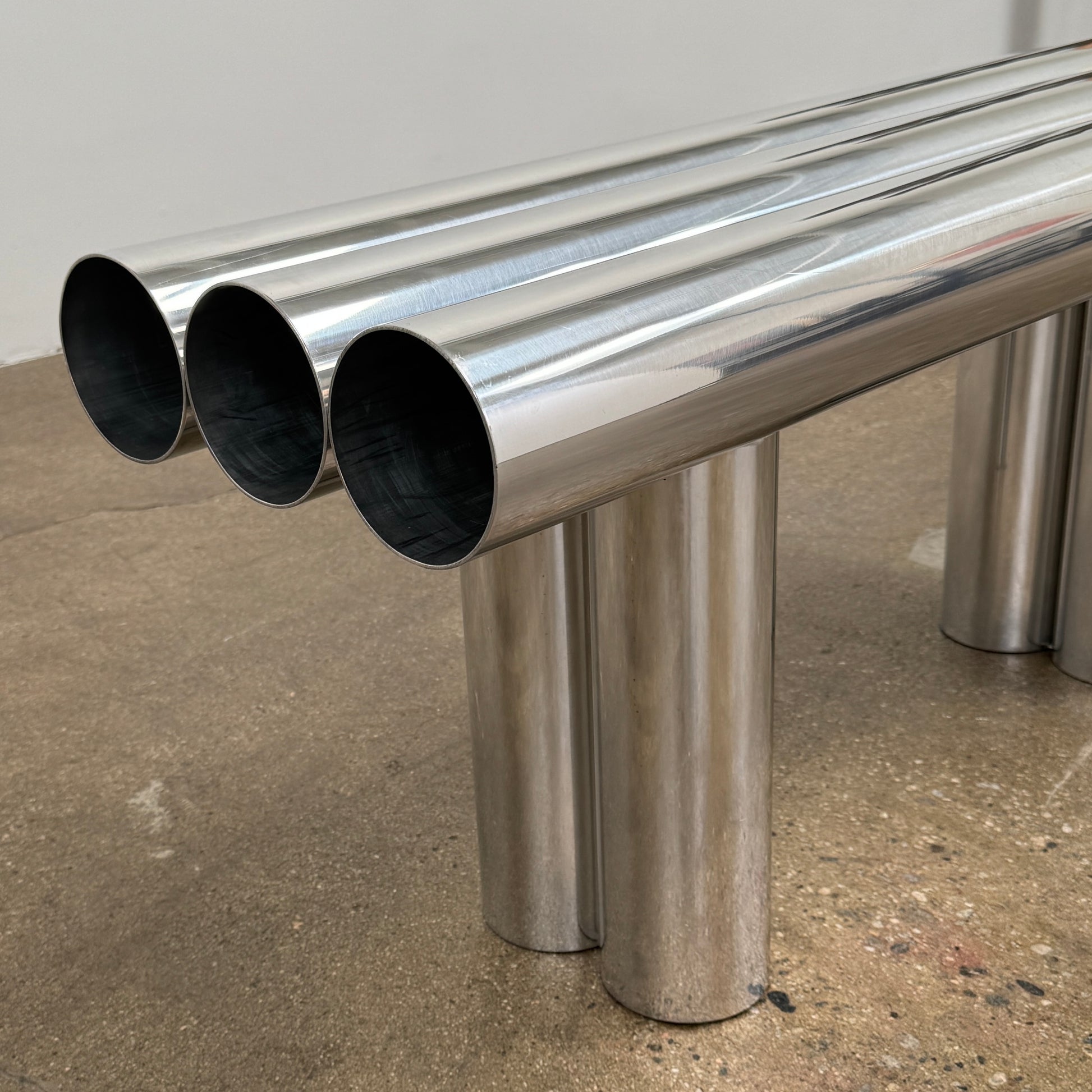 The Future Perfect's Septem Bench by Axel Chay features three cylindrical polished metal seats and matching legs in a Mediterranean-inspired design, shown against a plain white background.