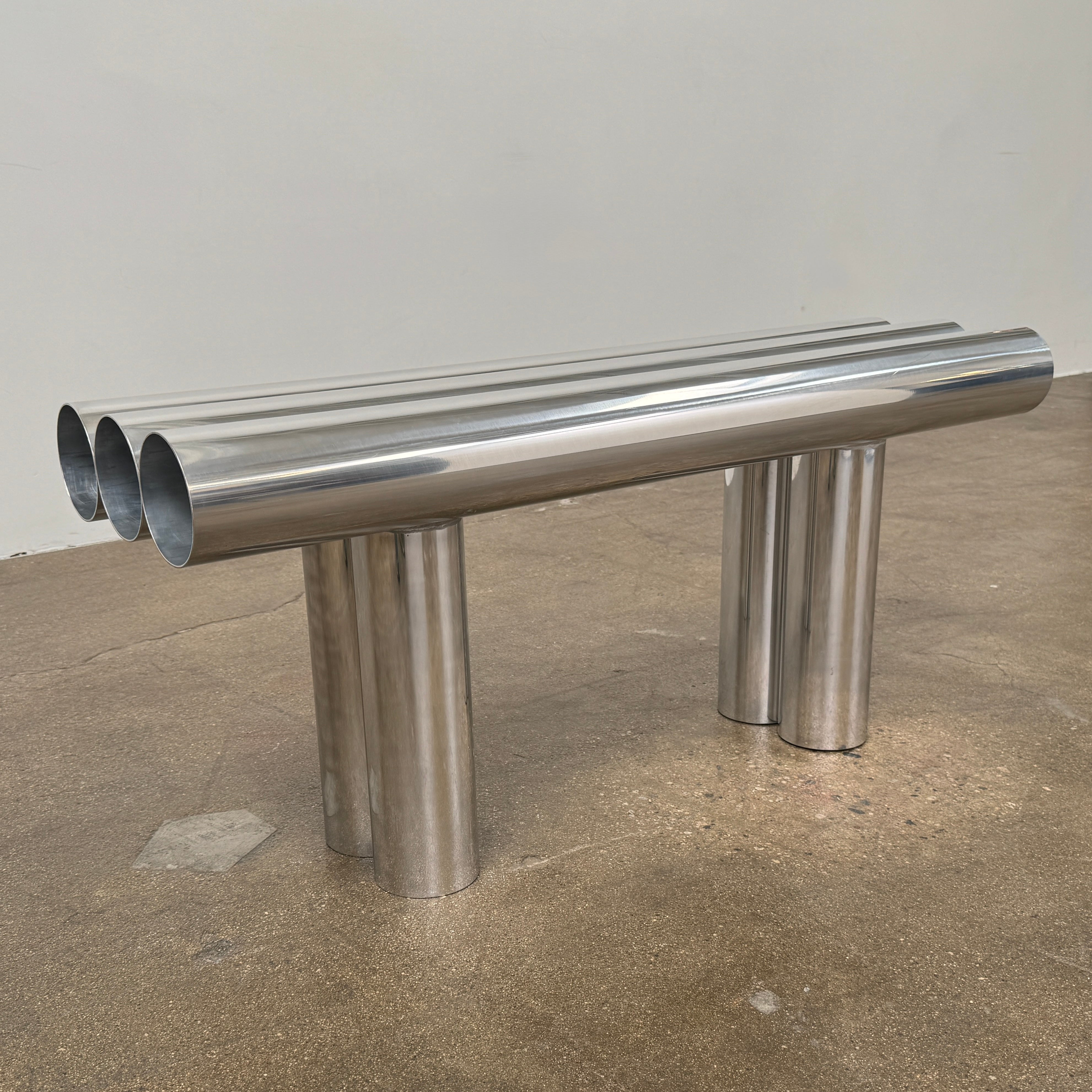 The Future Perfect's Septem Bench by Axel Chay features three cylindrical polished metal seats and matching legs in a Mediterranean-inspired design, shown against a plain white background.