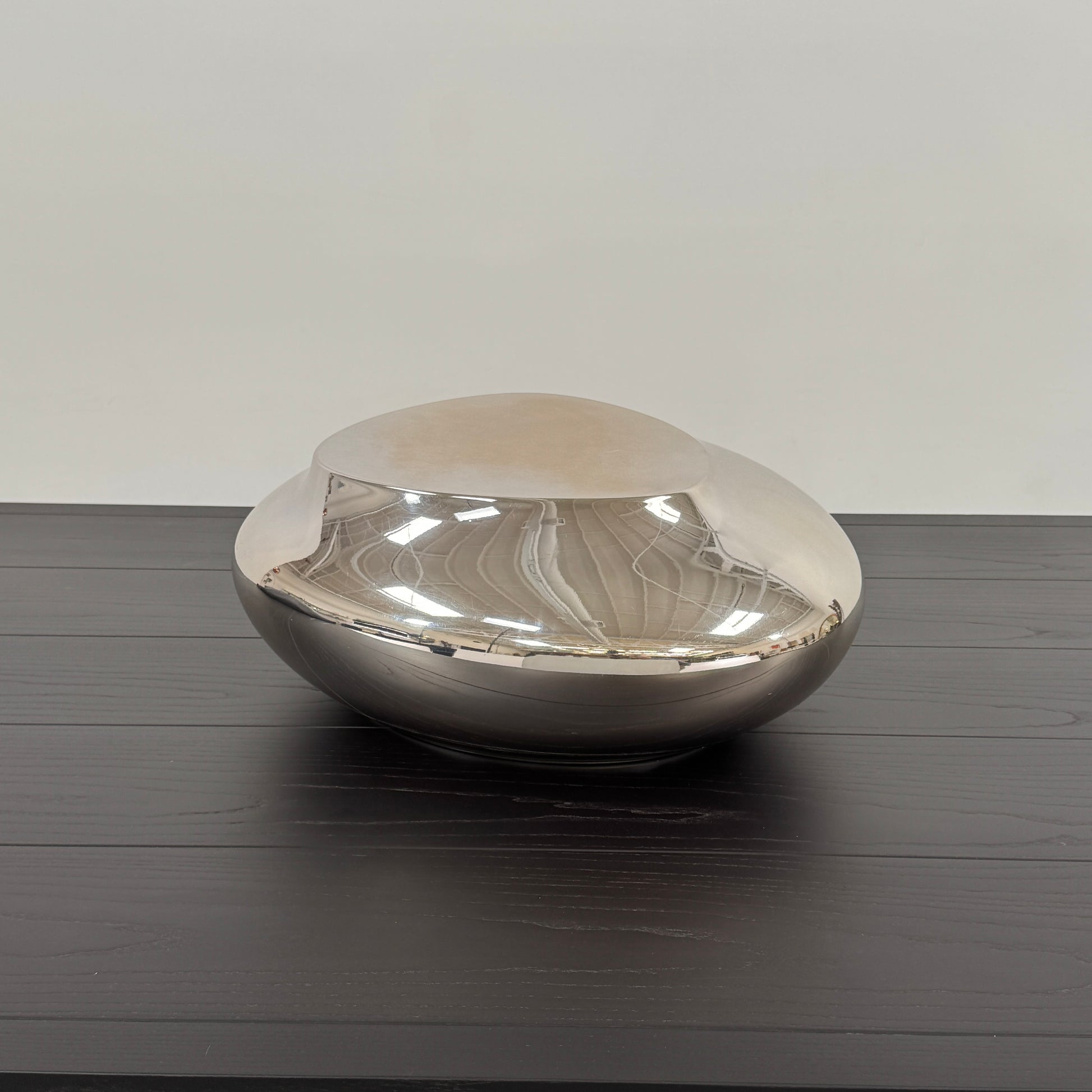 The Roche Bobois cute cut | XXS Cocktail table, with its round, reflective silver surface and smooth, unique shape, stands elegantly against a plain white background—an ideal accent for modern interiors.