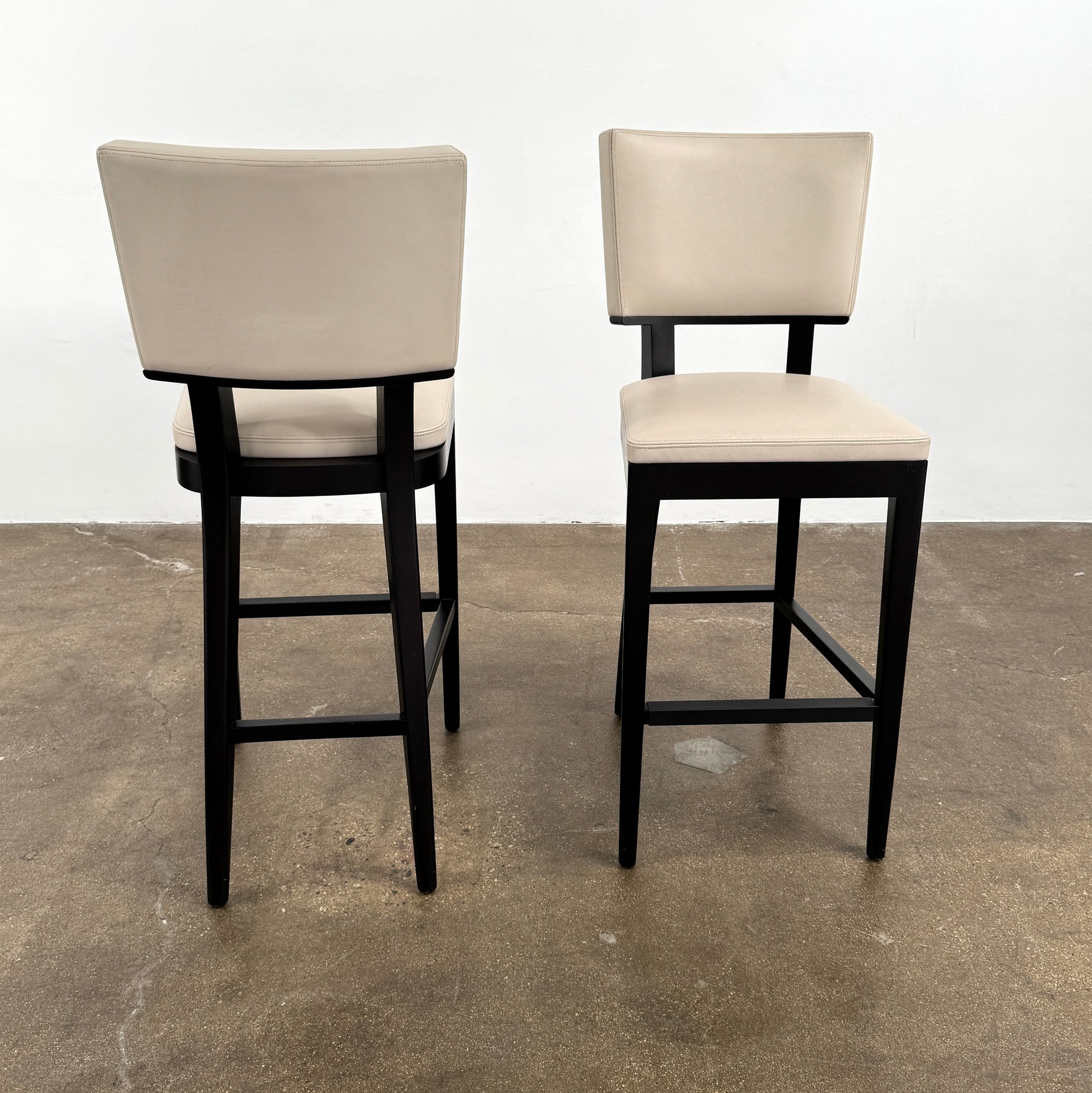Modern kitchen featuring a minimalist luxury vibe—Christian Liagre Bar Stool Set of 2 at the counter, large windows draped with sheer white curtains, and a stunning cityscape view outside.