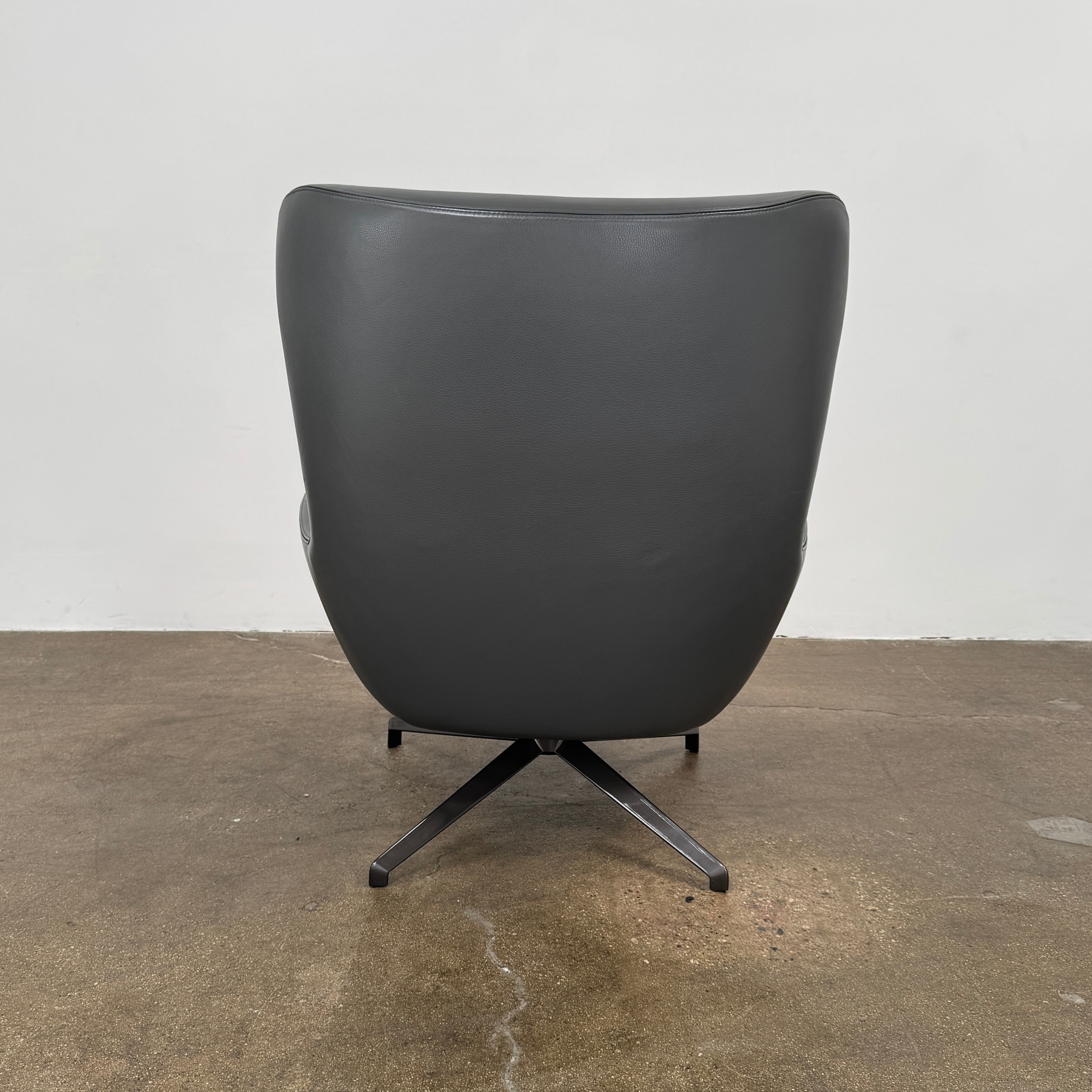 The Minotti Jensen Swivel Armchair features black leather upholstery, a high backrest, and angled metal legs by Minotti, displayed against a plain white background.