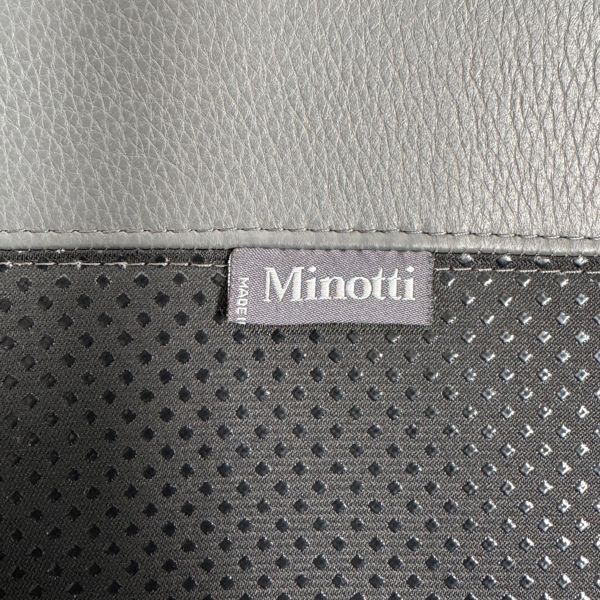 The Minotti Jensen Swivel Armchair features black leather upholstery, a high backrest, and angled metal legs by Minotti, displayed against a plain white background.