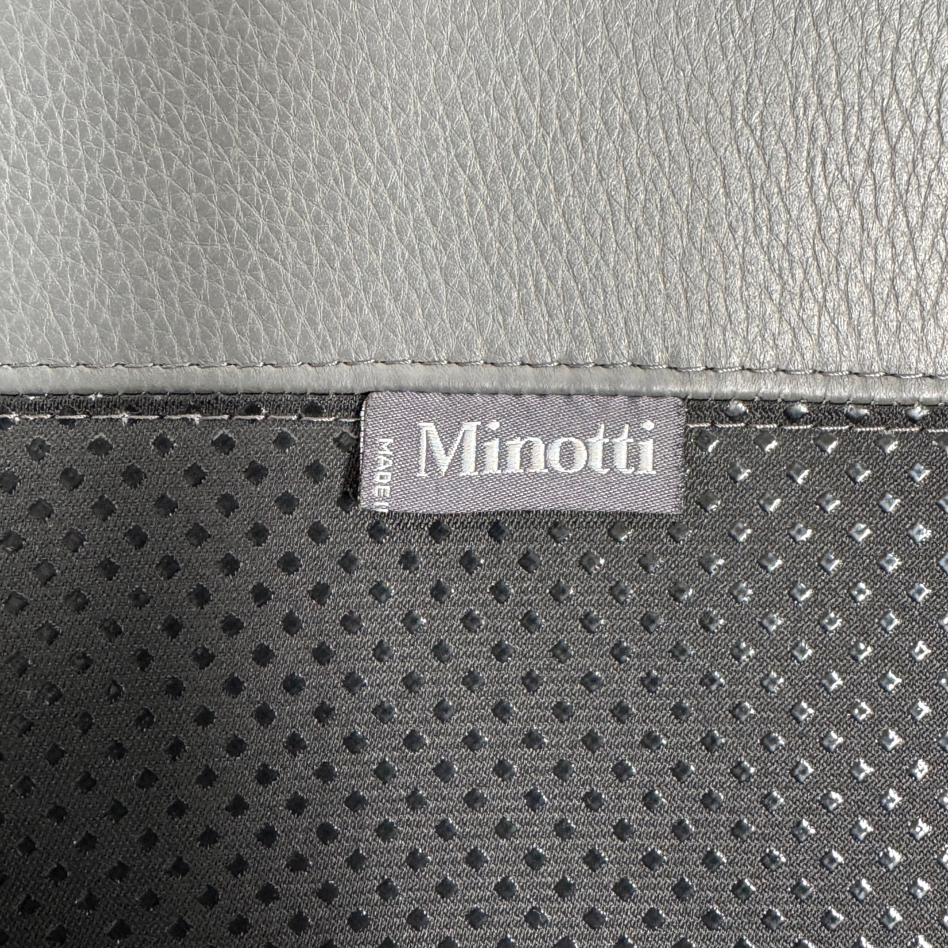 The Minotti Jensen Swivel Armchair features black leather upholstery, a high backrest, and angled metal legs by Minotti, displayed against a plain white background.