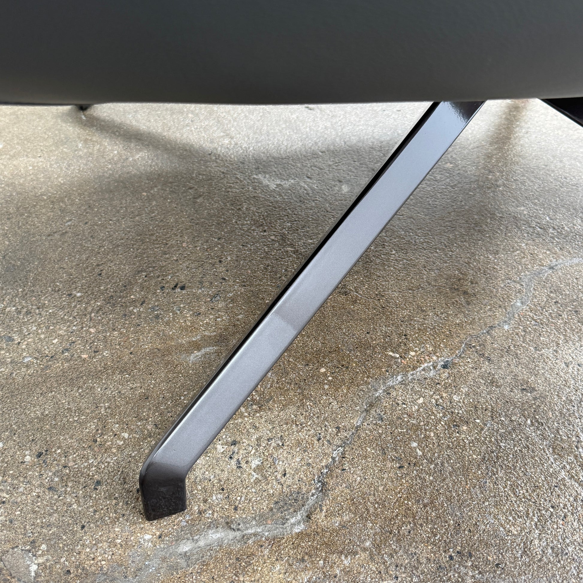 The Minotti Jensen Swivel Armchair features black leather upholstery, a high backrest, and angled metal legs by Minotti, displayed against a plain white background.