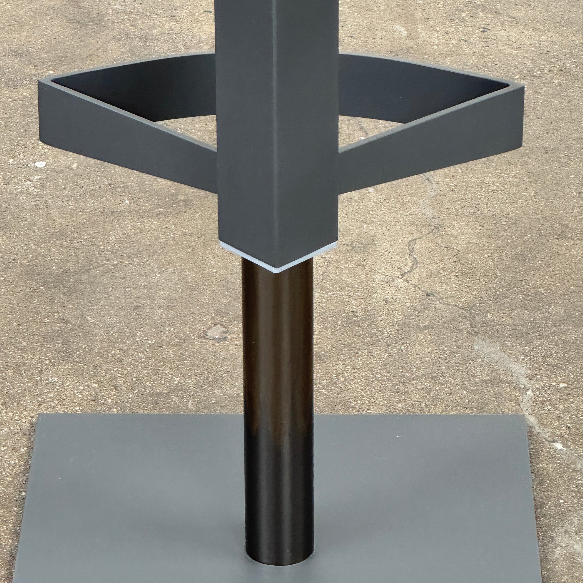 The Cantoni Wing Barstool by Cantoni features a modern black swivel design with a metal base, set on a brown concrete floor against a plain white wall.