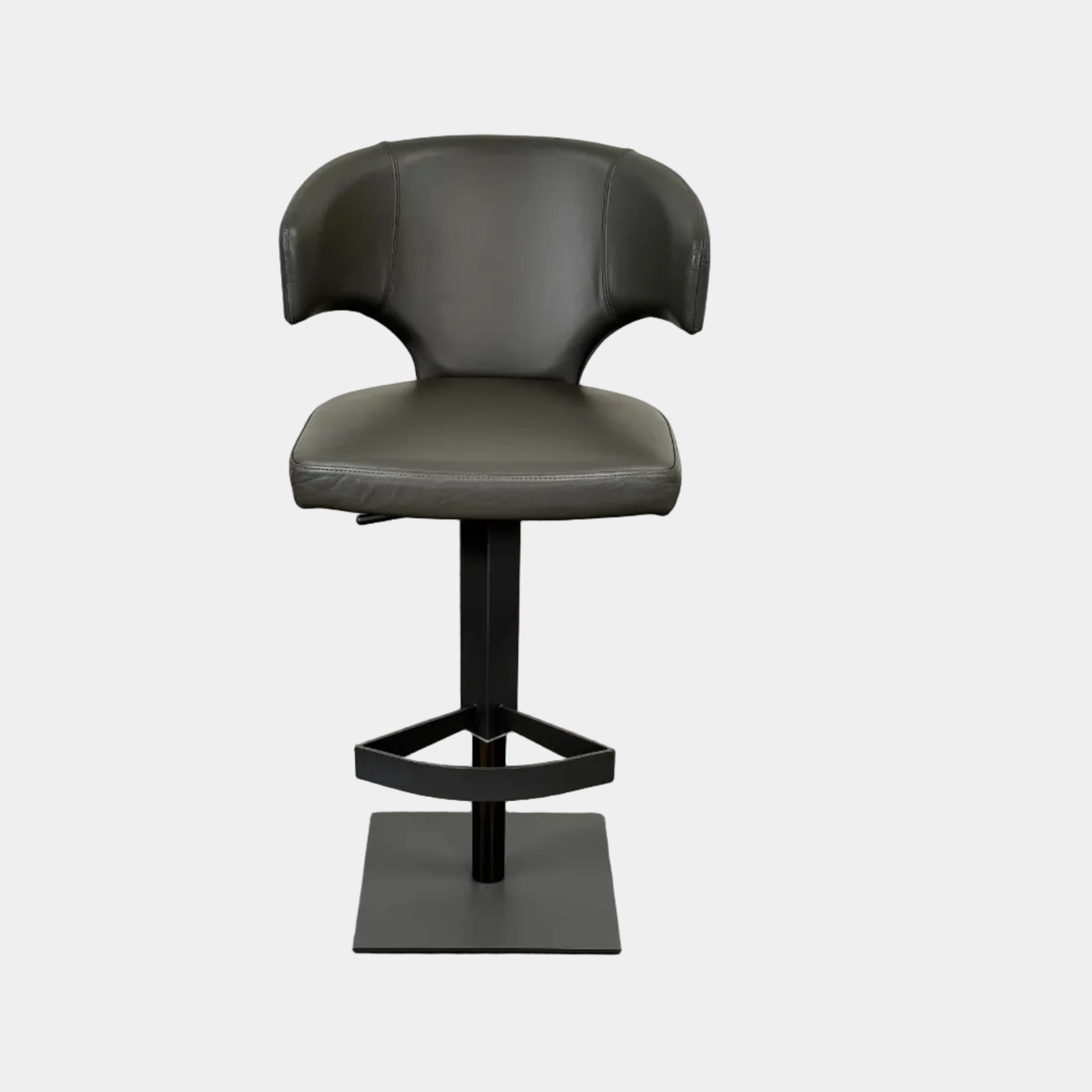 The Cantoni Wing Barstool by Cantoni features a modern black swivel design with a metal base, set on a brown concrete floor against a plain white wall.