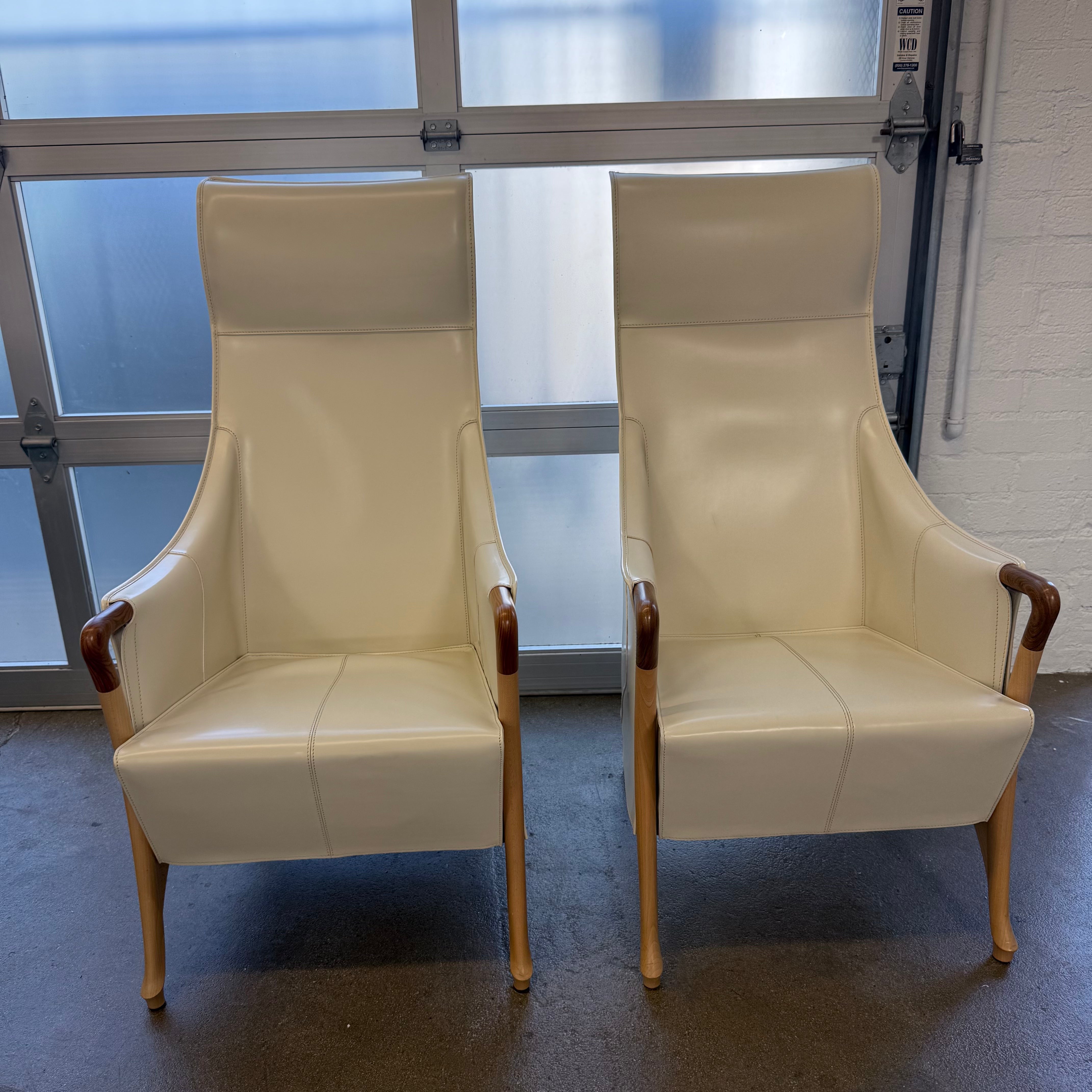 The Giorgetti “Progetti” Bergère / High-Back Lounge Chair by Giorgetti features light beige upholstery, wooden armrests and legs, and elegant ivory saddle leather accents, all inspired by the sophisticated Progetti collection, and is showcased against a plain white background.