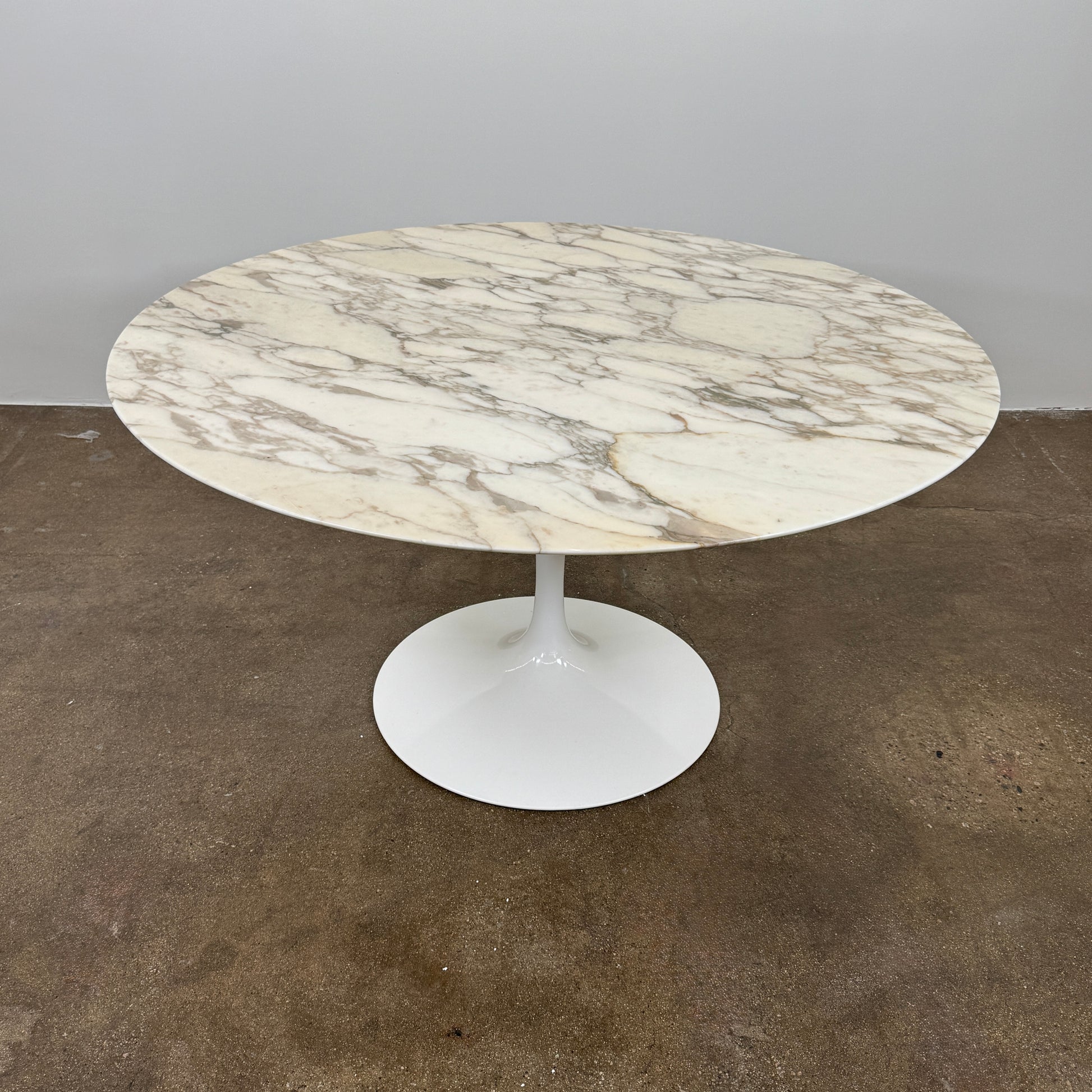 The Knoll Saarinen Table 54" Round Arabescato Marble features a white base and pedestal stand, inspired by the original Knoll design and shown isolated on a white background.