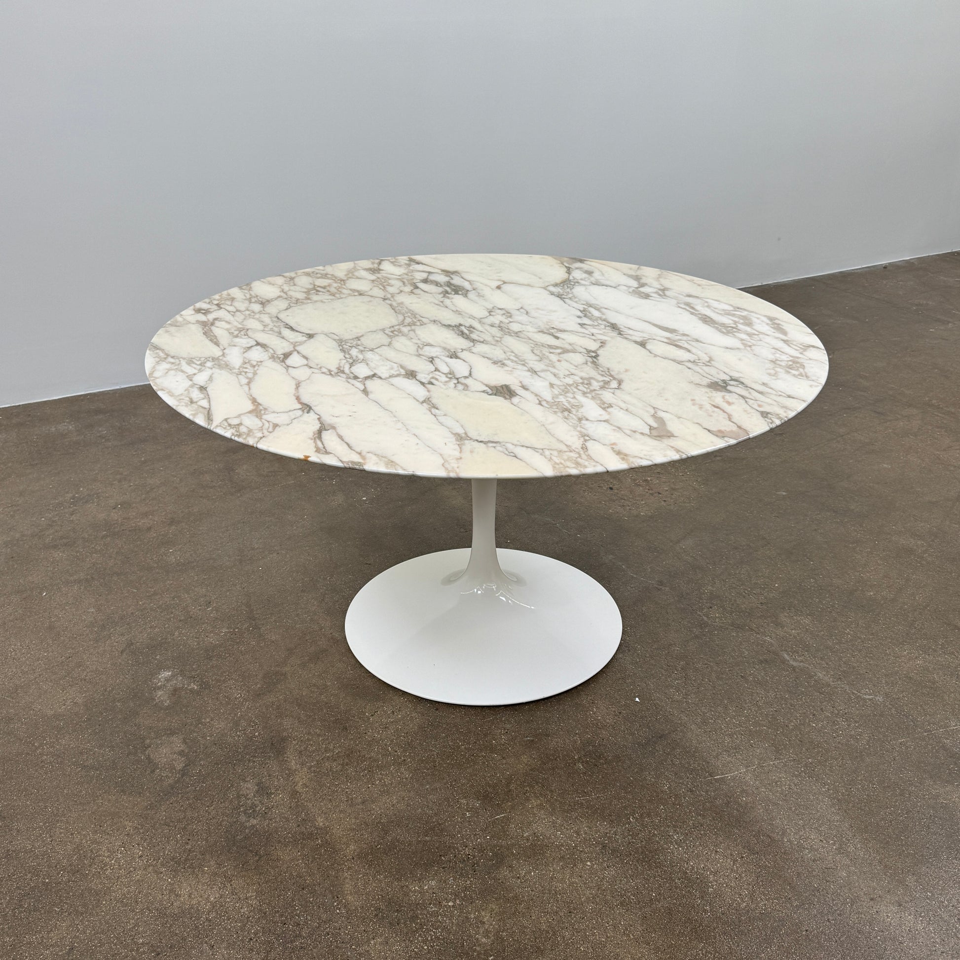 The Knoll Saarinen Table 54" Round Arabescato Marble features a white base and pedestal stand, inspired by the original Knoll design and shown isolated on a white background.