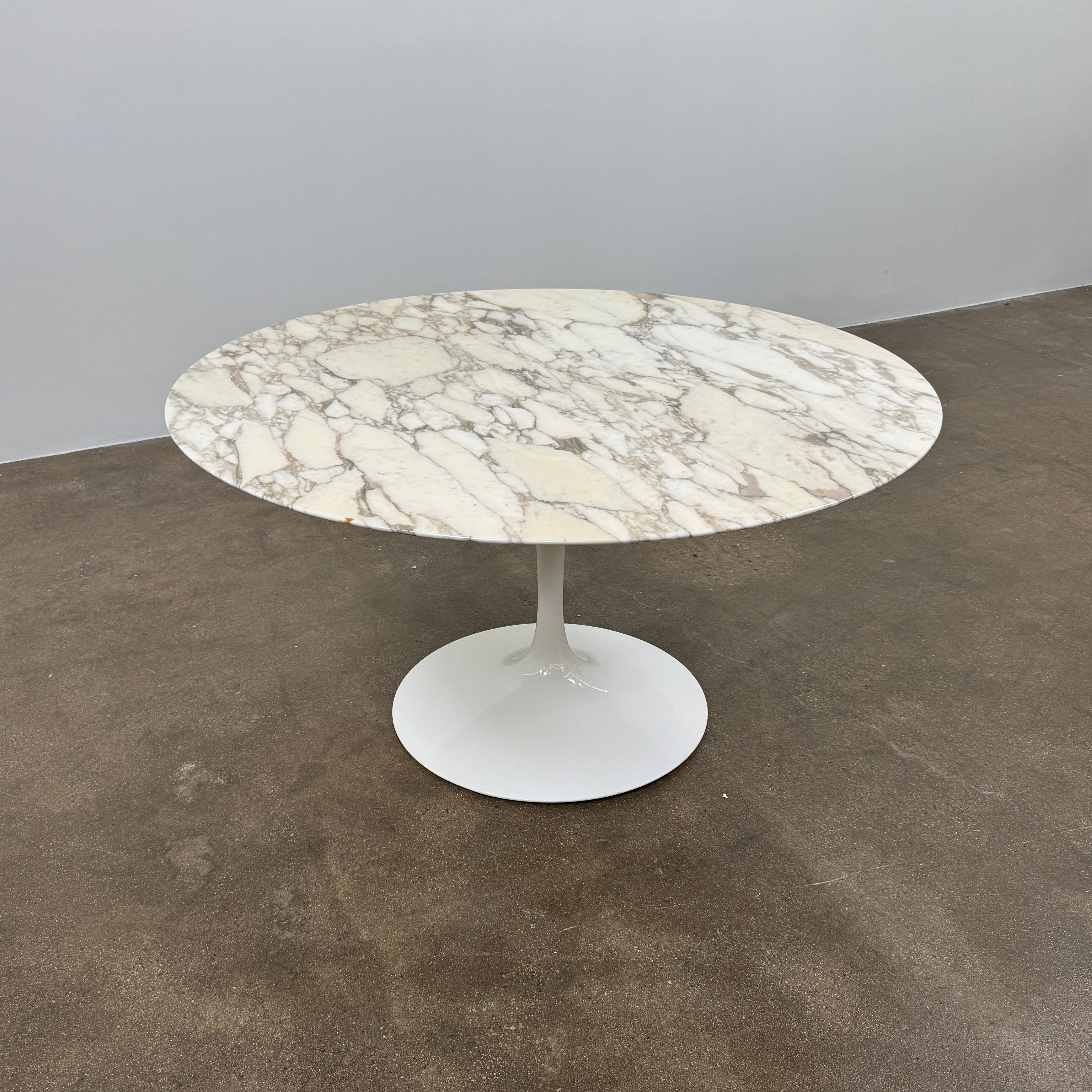 The Knoll Saarinen Table 54" Round Arabescato Marble features a white base and pedestal stand, inspired by the original Knoll design and shown isolated on a white background.