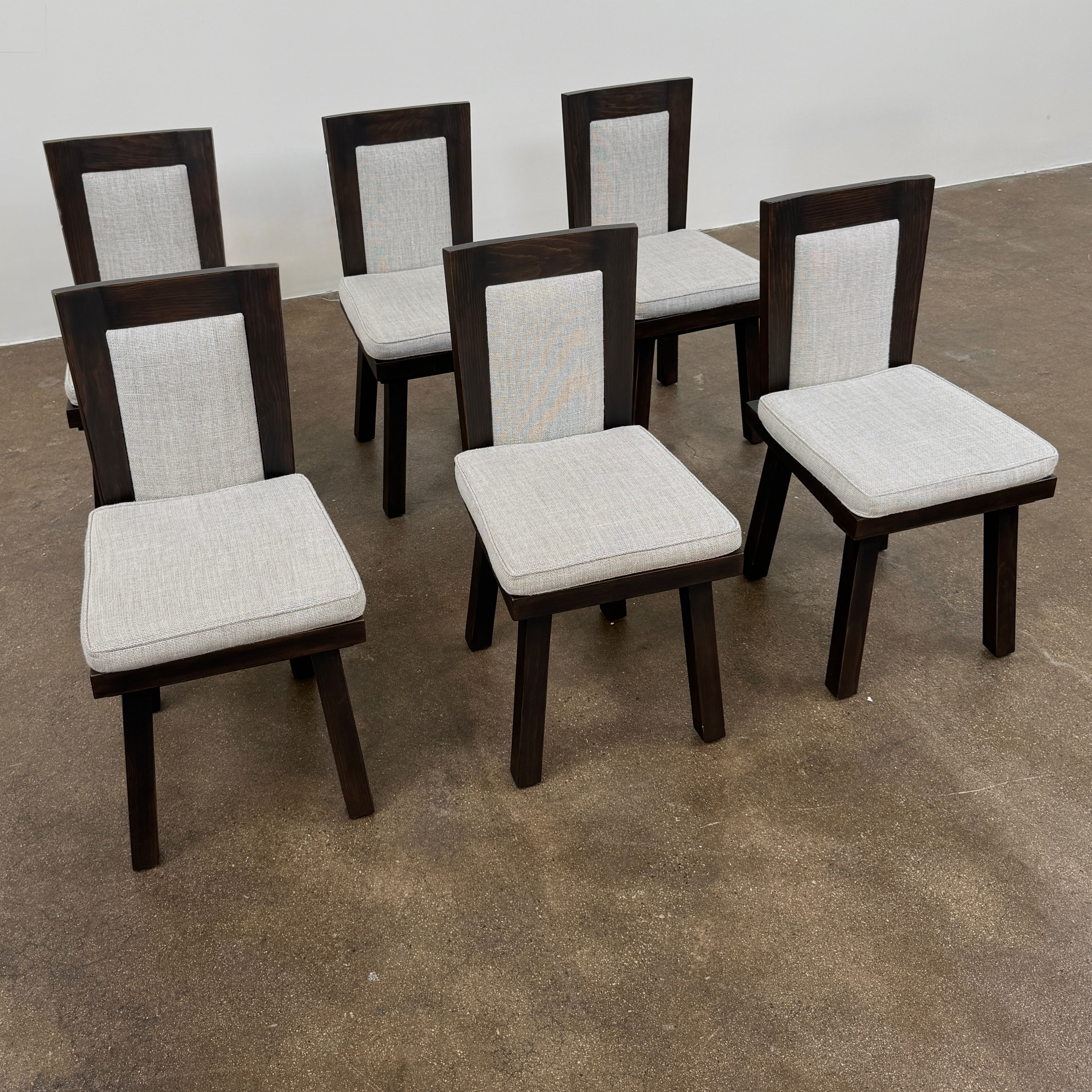 Six Waldo's Designs Custom Pine Dining Chairs (Set of 6) with light upholstered seats and backs are arranged in two rows on a bare concrete floor against a plain white wall.