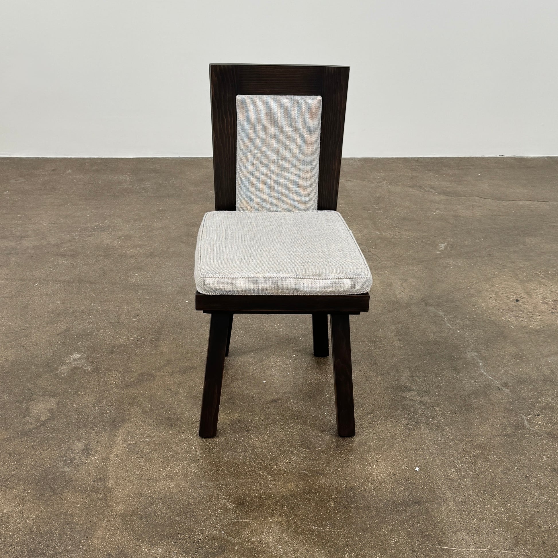 Six Waldo's Designs Custom Pine Dining Chairs (Set of 6) with light upholstered seats and backs are arranged in two rows on a bare concrete floor against a plain white wall.
