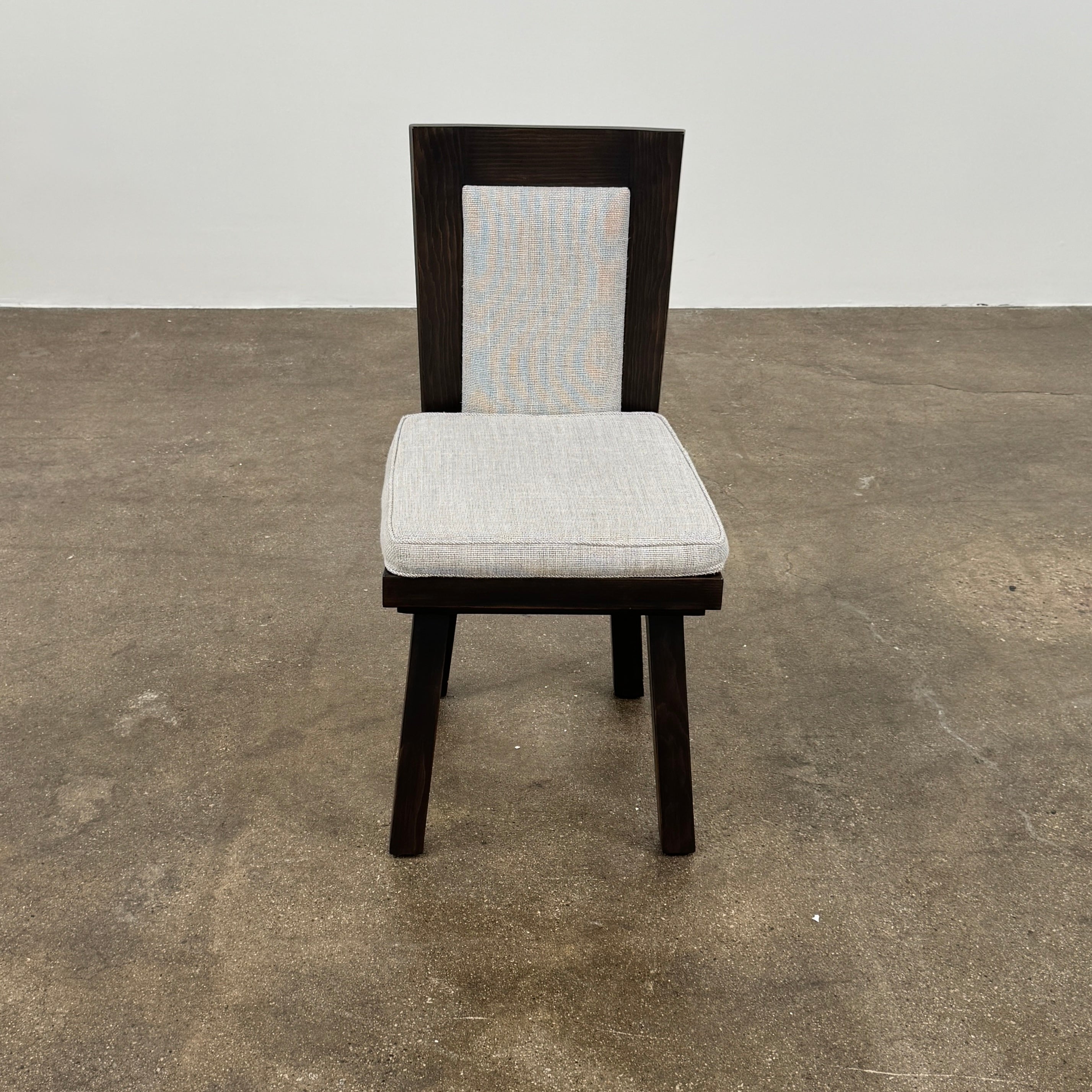Six Waldo's Designs Custom Pine Dining Chairs (Set of 6) with light upholstered seats and backs are arranged in two rows on a bare concrete floor against a plain white wall.