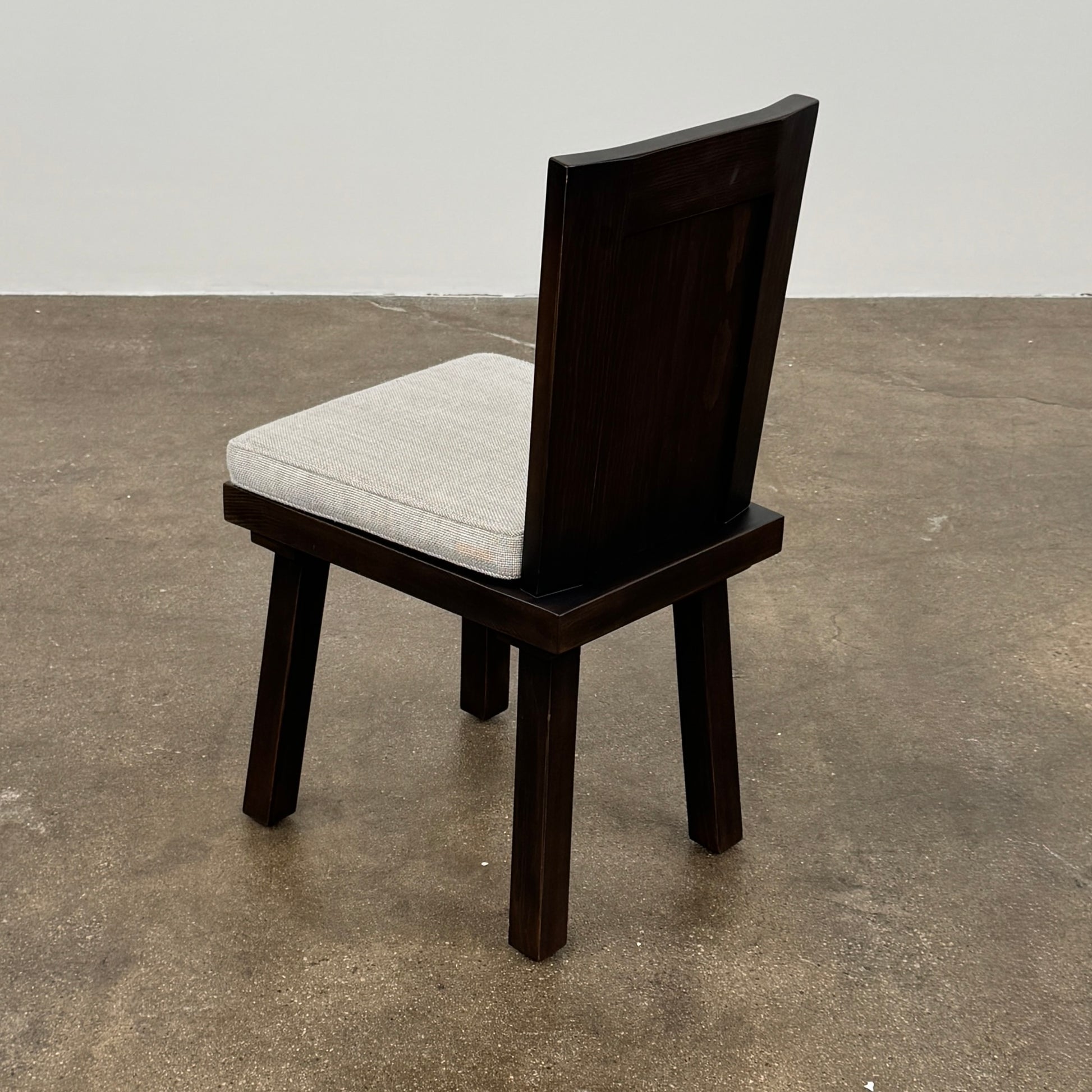 Six Waldo's Designs Custom Pine Dining Chairs (Set of 6) with light upholstered seats and backs are arranged in two rows on a bare concrete floor against a plain white wall.
