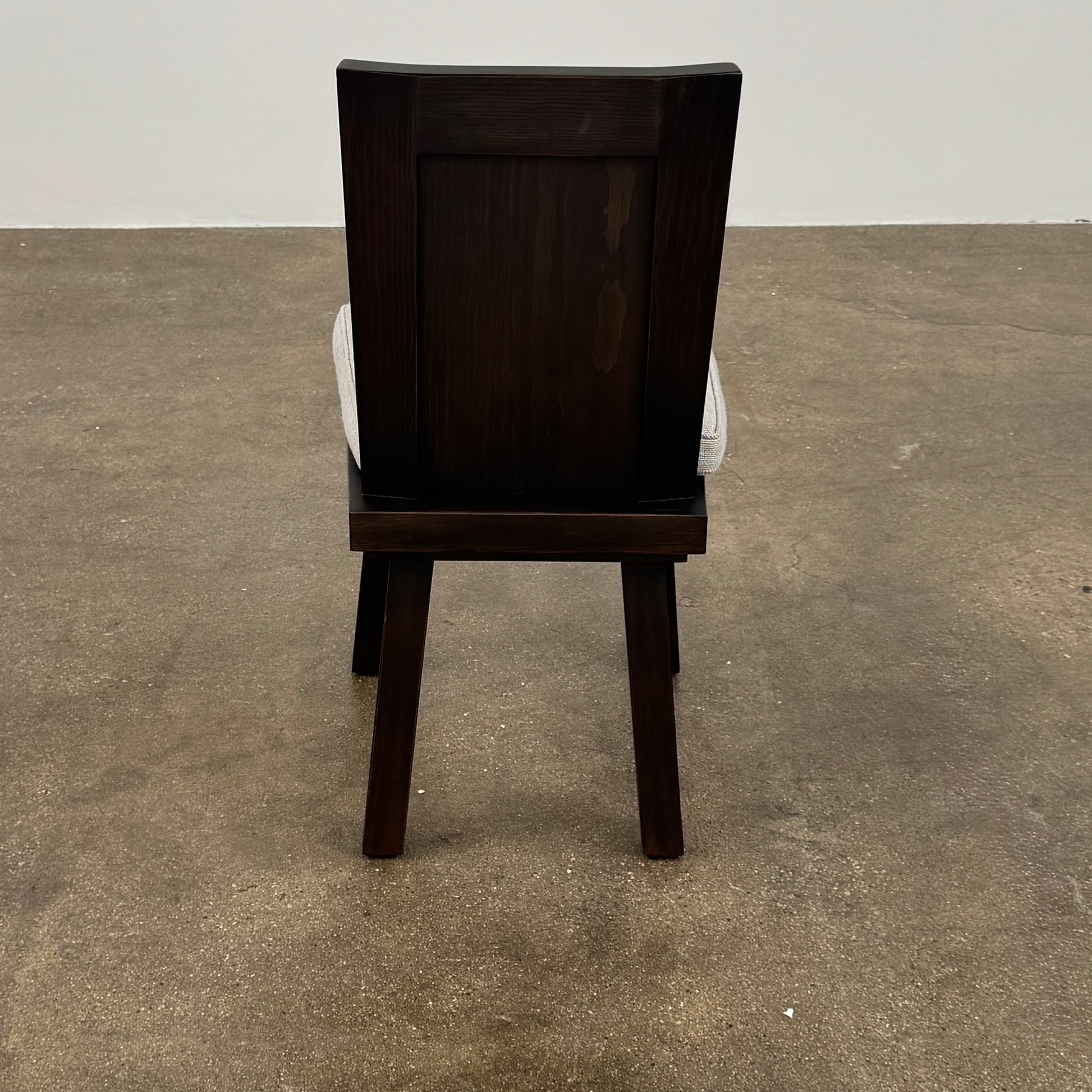 Six Waldo's Designs Custom Pine Dining Chairs (Set of 6) with light upholstered seats and backs are arranged in two rows on a bare concrete floor against a plain white wall.