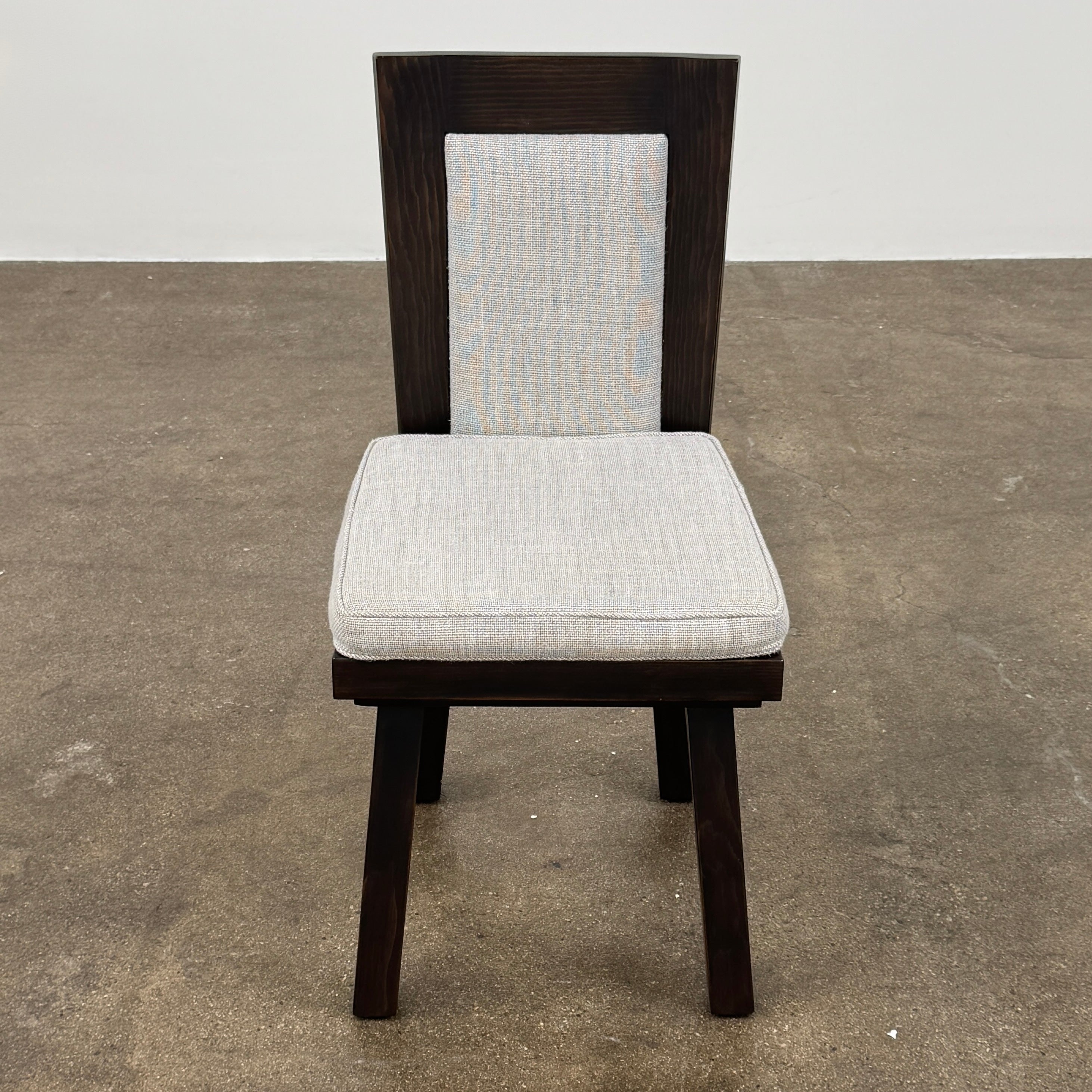 Six Waldo's Designs Custom Pine Dining Chairs (Set of 6) with light upholstered seats and backs are arranged in two rows on a bare concrete floor against a plain white wall.