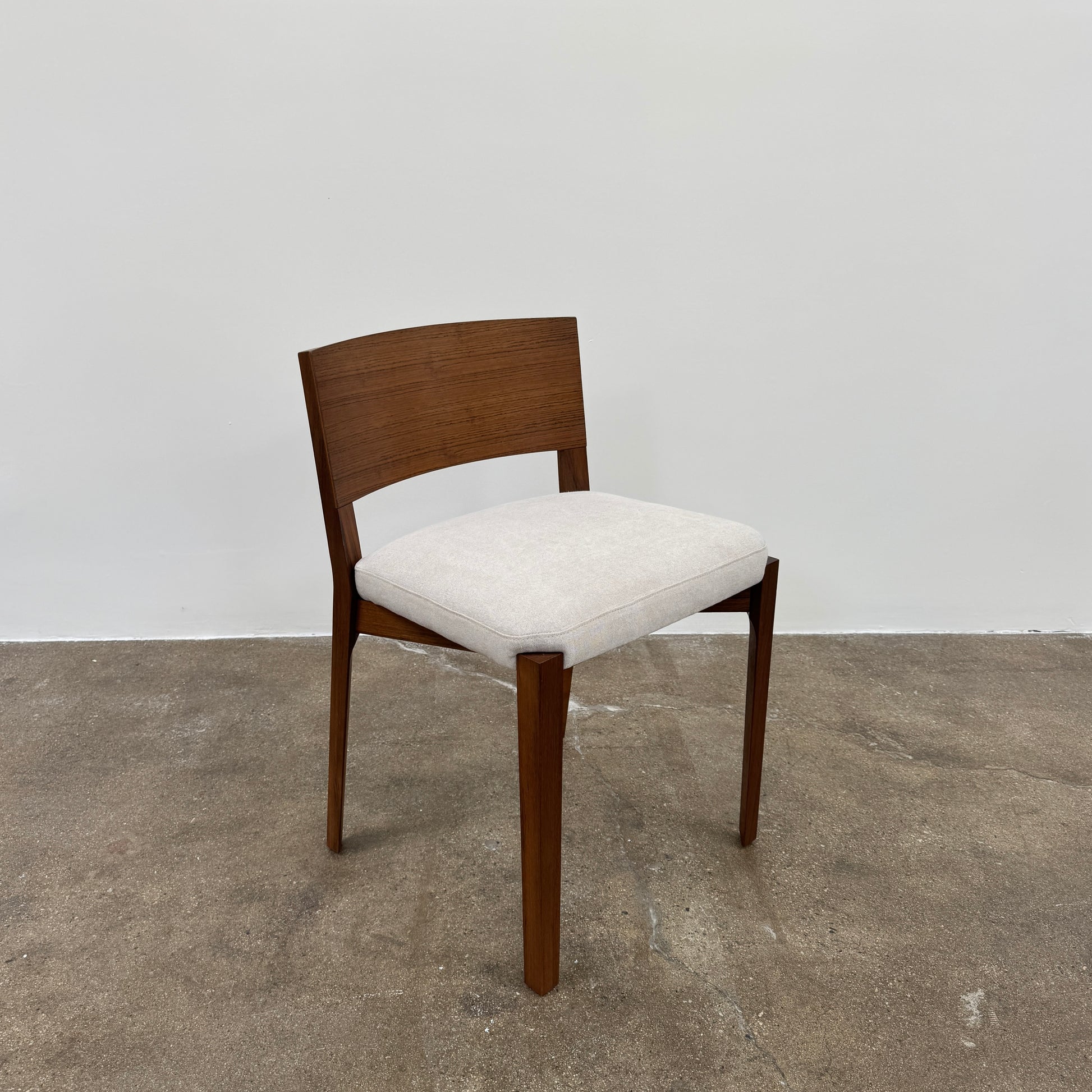 A set of 8 Porro Lario dining chairs by Porro, featuring minimalist armrests and light-cushioned seats, sits on a concrete floor against a plain white wall, reflecting refined contemporary style.