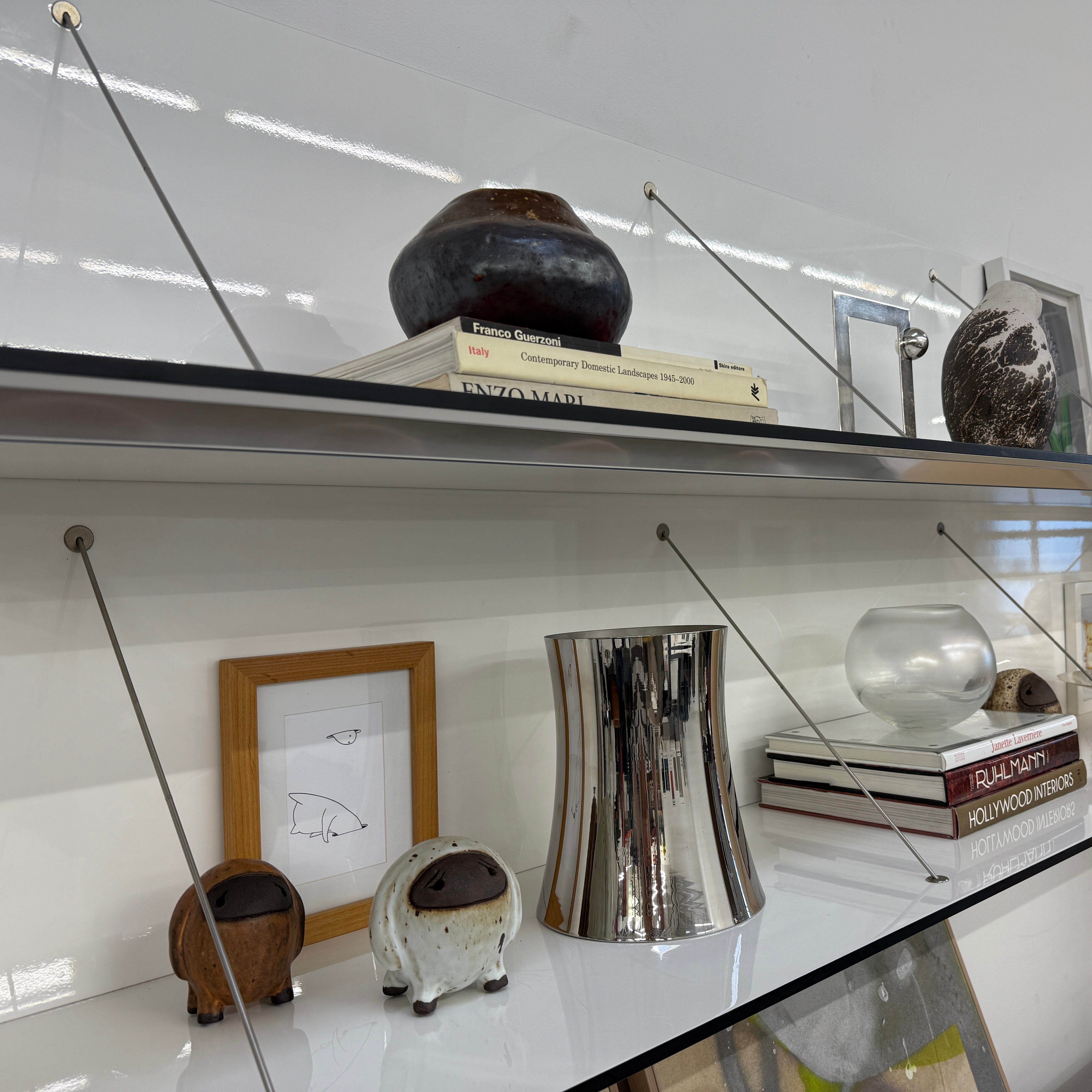 Two long, empty black shelves from the B&B Italia PAB Shelving collection are mounted on a white wall, supported by evenly spaced metal brackets.