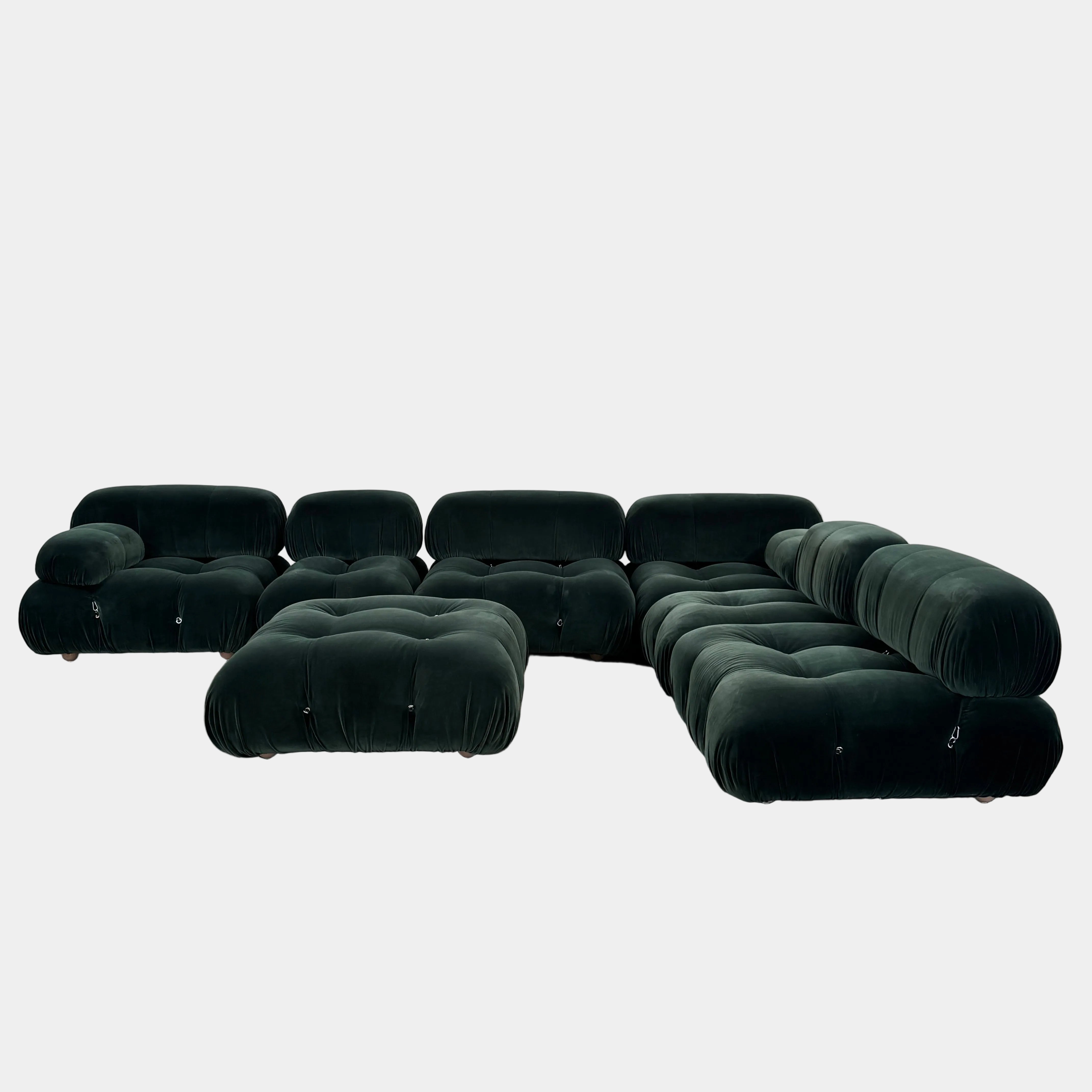 The B&B Italia Camaleonda 7 Piece Modular Sofa by B&B Italia features tufted dark green velvet, multiple connected seats, and one armrest, inspired by the original Camaleonda design, set against a plain white background.