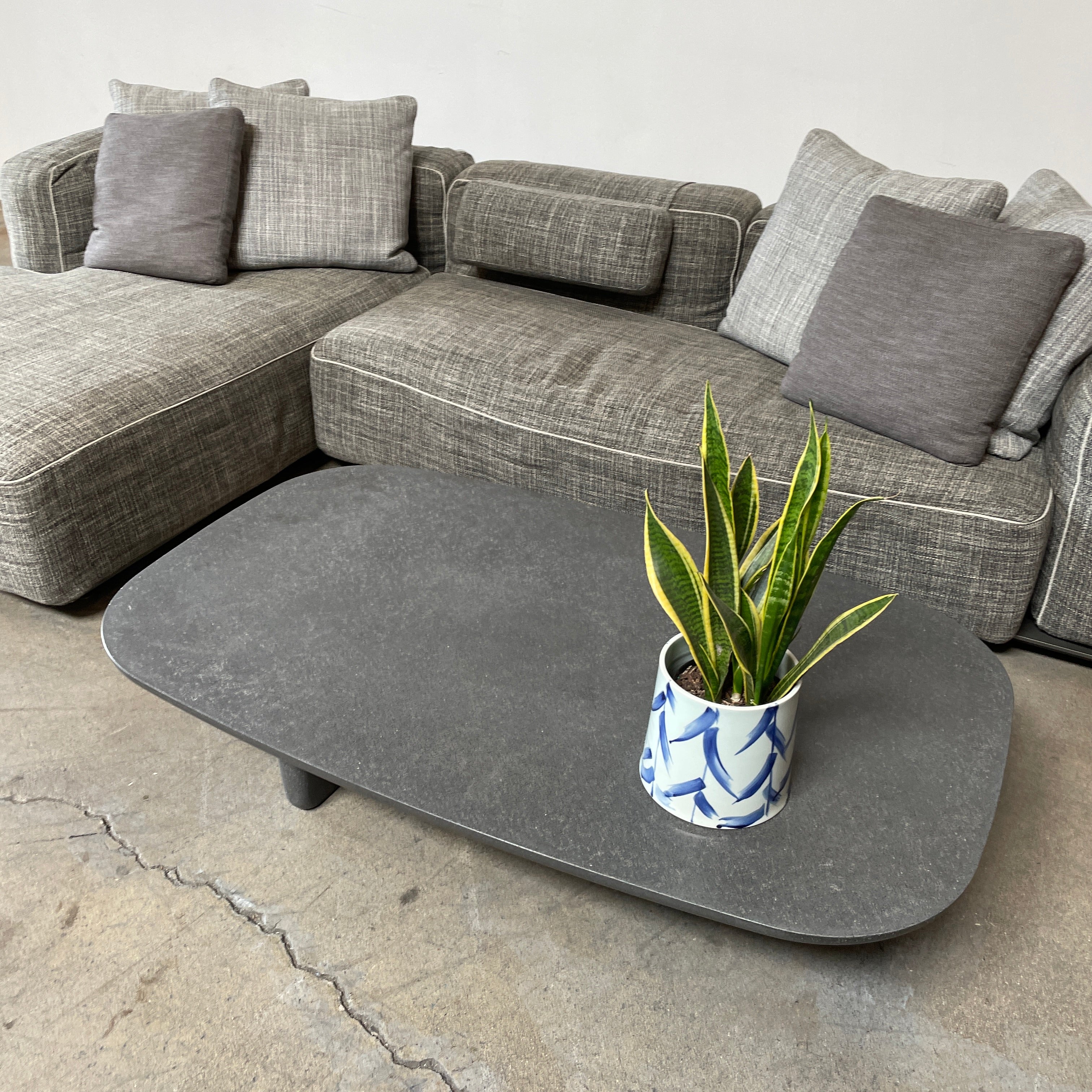 A rectangular black coffee table with asymmetrical supports on a white background, reminiscent of the B&B Italia Tobi-Ishi Outdoor Coffee Table (hold) by B&B Italia.