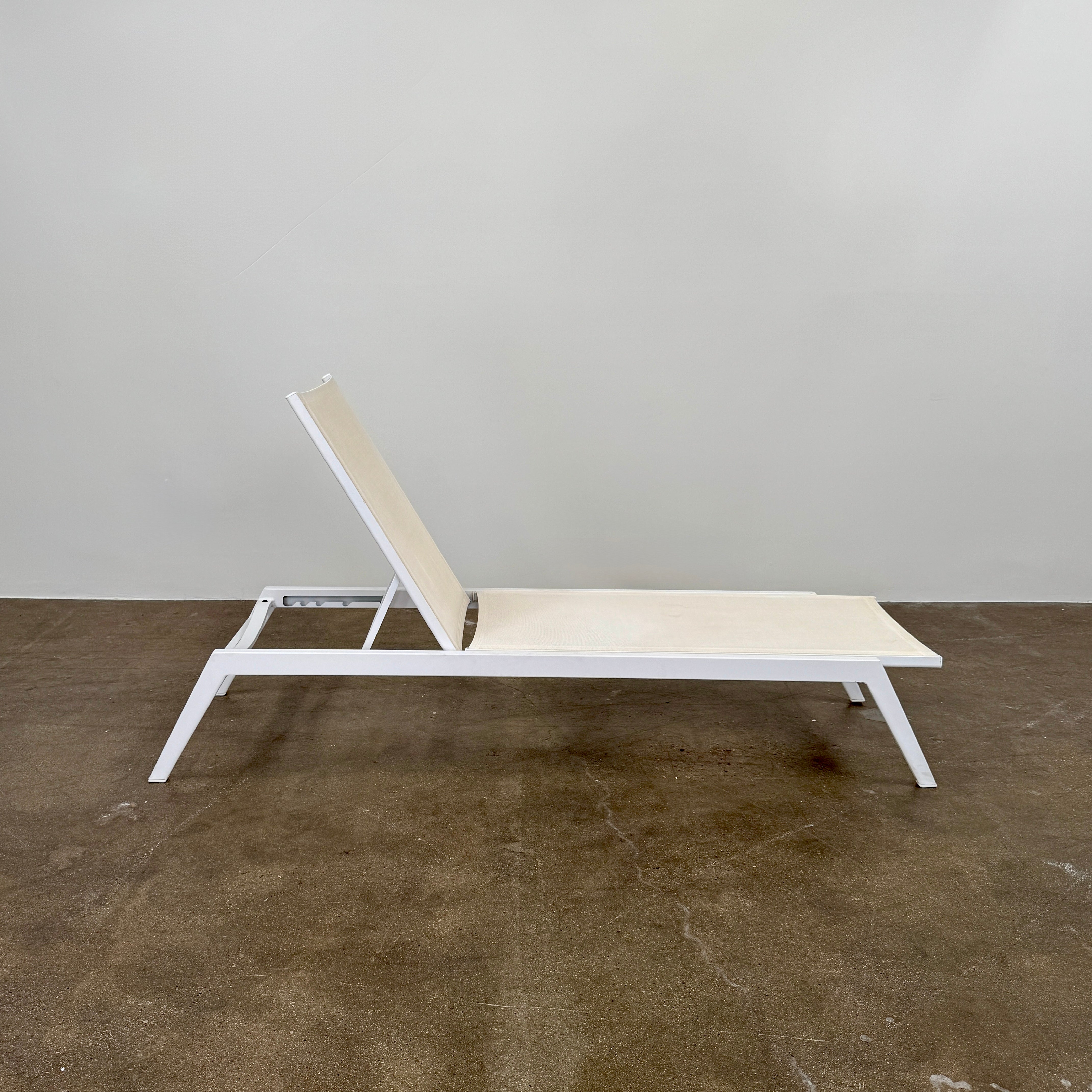 The Serge Ferrari Sun Lounger is a white, modern piece with an adjustable backrest, crafted from metal and mesh using durable Serge Ferrari fabric, shown on a plain white background.
