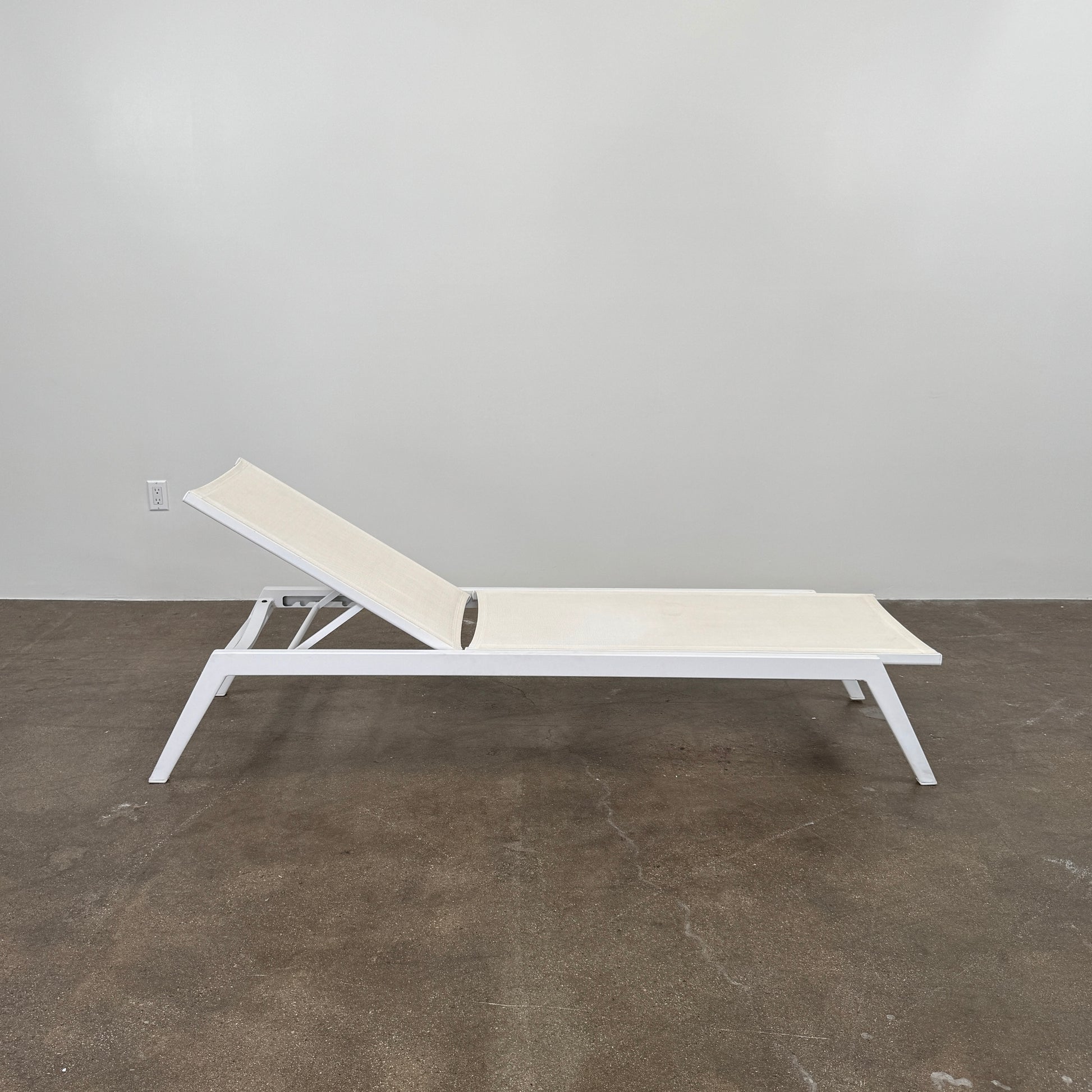 The Serge Ferrari Sun Lounger is a white, modern piece with an adjustable backrest, crafted from metal and mesh using durable Serge Ferrari fabric, shown on a plain white background.