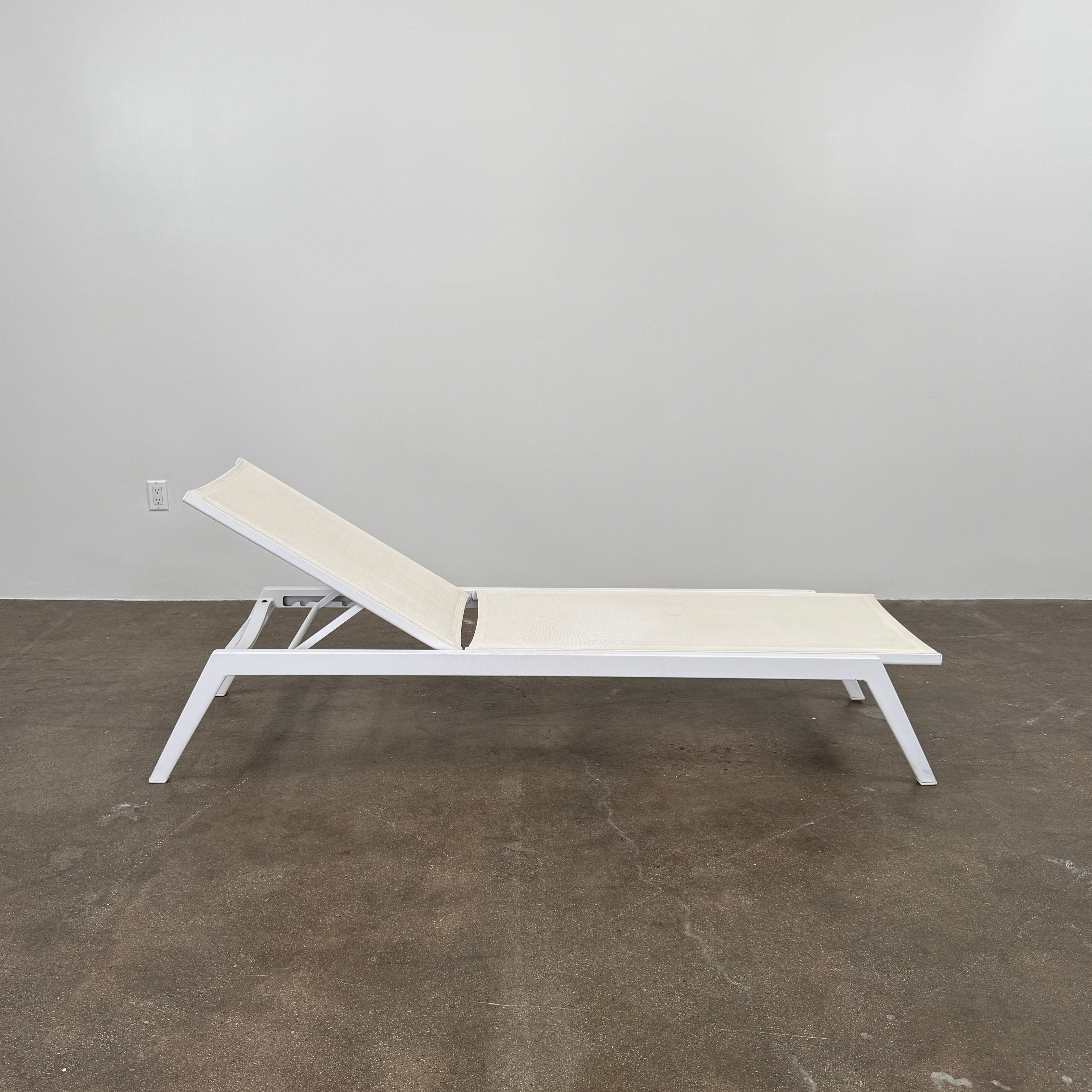 The Serge Ferrari Sun Lounger is a white, modern piece with an adjustable backrest, crafted from metal and mesh using durable Serge Ferrari fabric, shown on a plain white background.
