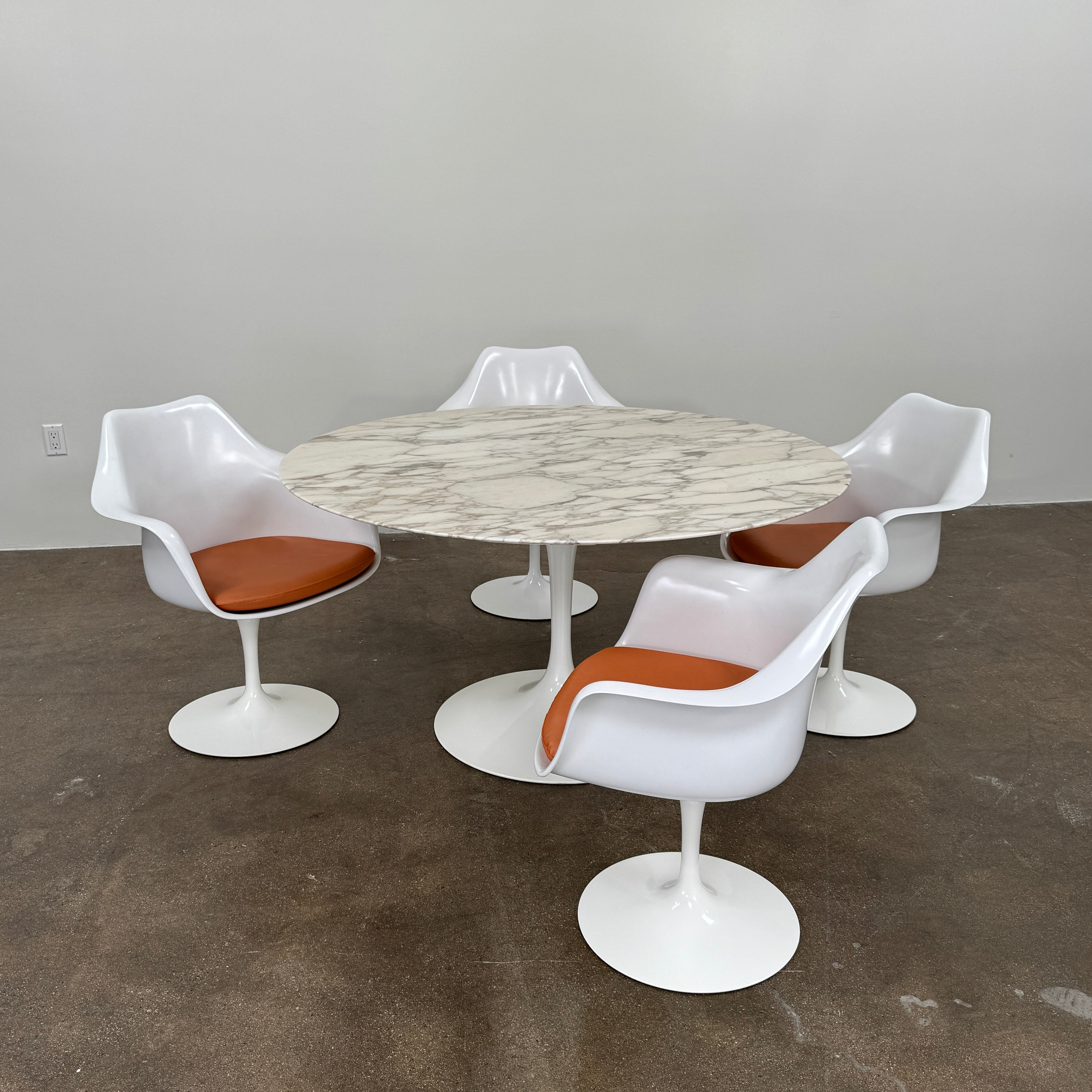 Four Knoll Saarinen Tulip Armchairs with brown vinyl seat cushions and pedestal bases, by Knoll, are arranged on a plain white background.