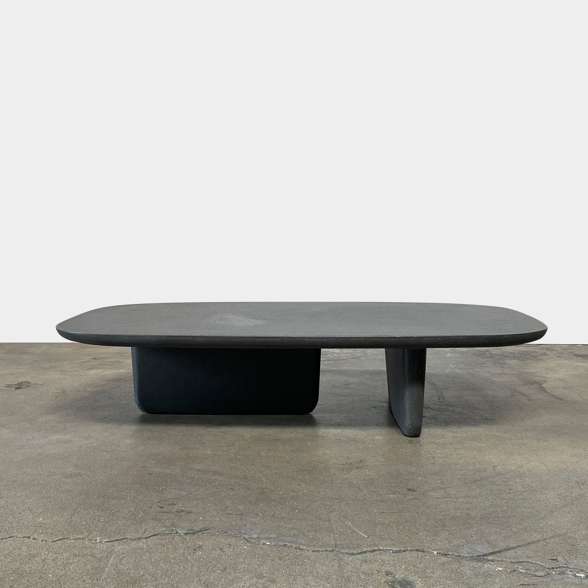 A rectangular black coffee table with asymmetrical supports on a white background, reminiscent of the B&B Italia Tobi-Ishi Outdoor Coffee Table (hold) by B&B Italia.