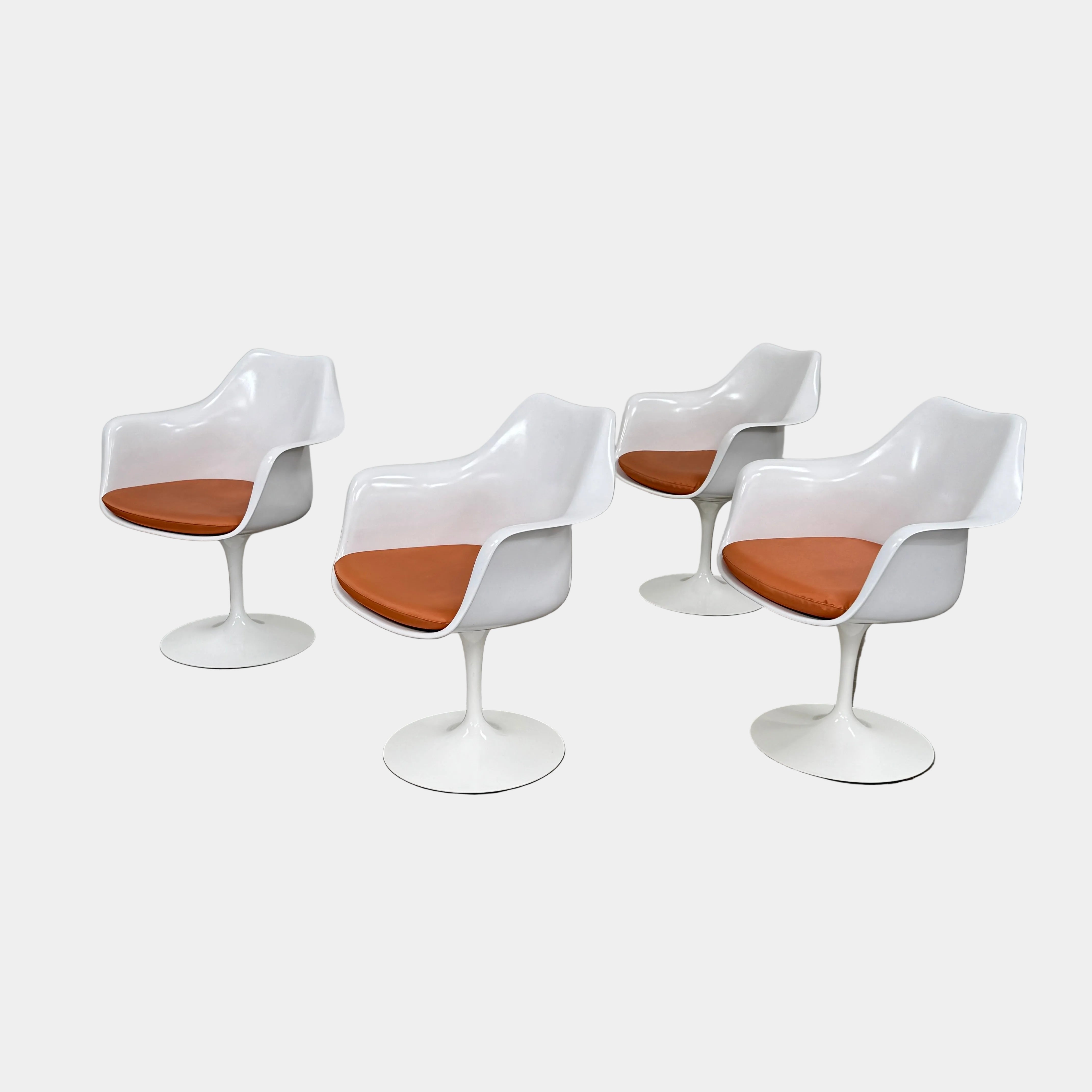 Four Knoll Saarinen Tulip Armchairs with brown vinyl seat cushions and pedestal bases, by Knoll, are arranged on a plain white background.