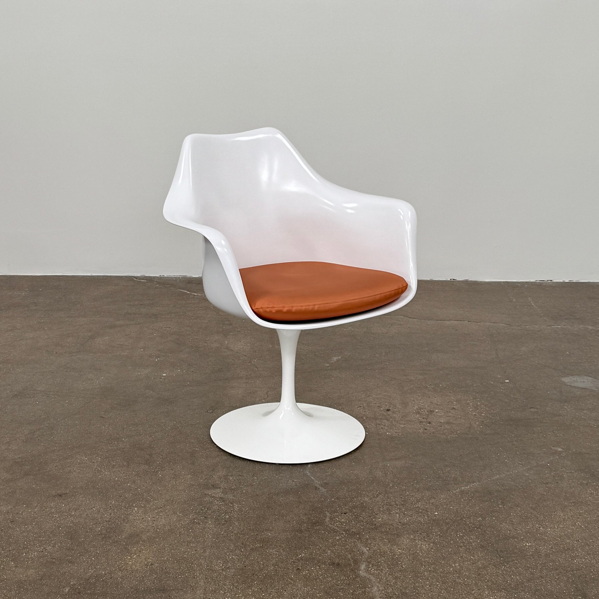 Four Knoll Saarinen Tulip Armchairs with brown vinyl seat cushions and pedestal bases, by Knoll, are arranged on a plain white background.
