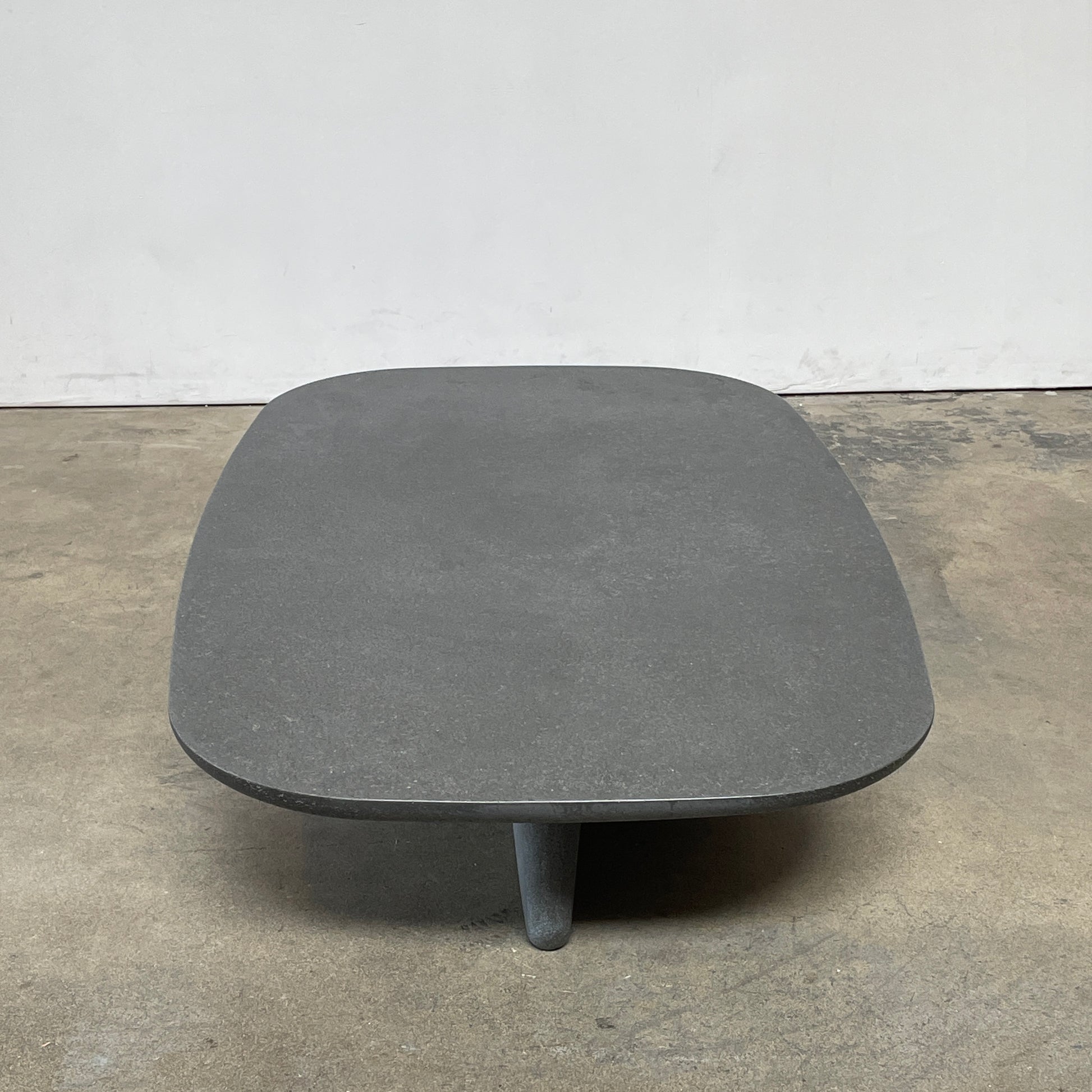 A rectangular black coffee table with asymmetrical supports on a white background, reminiscent of the B&B Italia Tobi-Ishi Outdoor Coffee Table (hold) by B&B Italia.